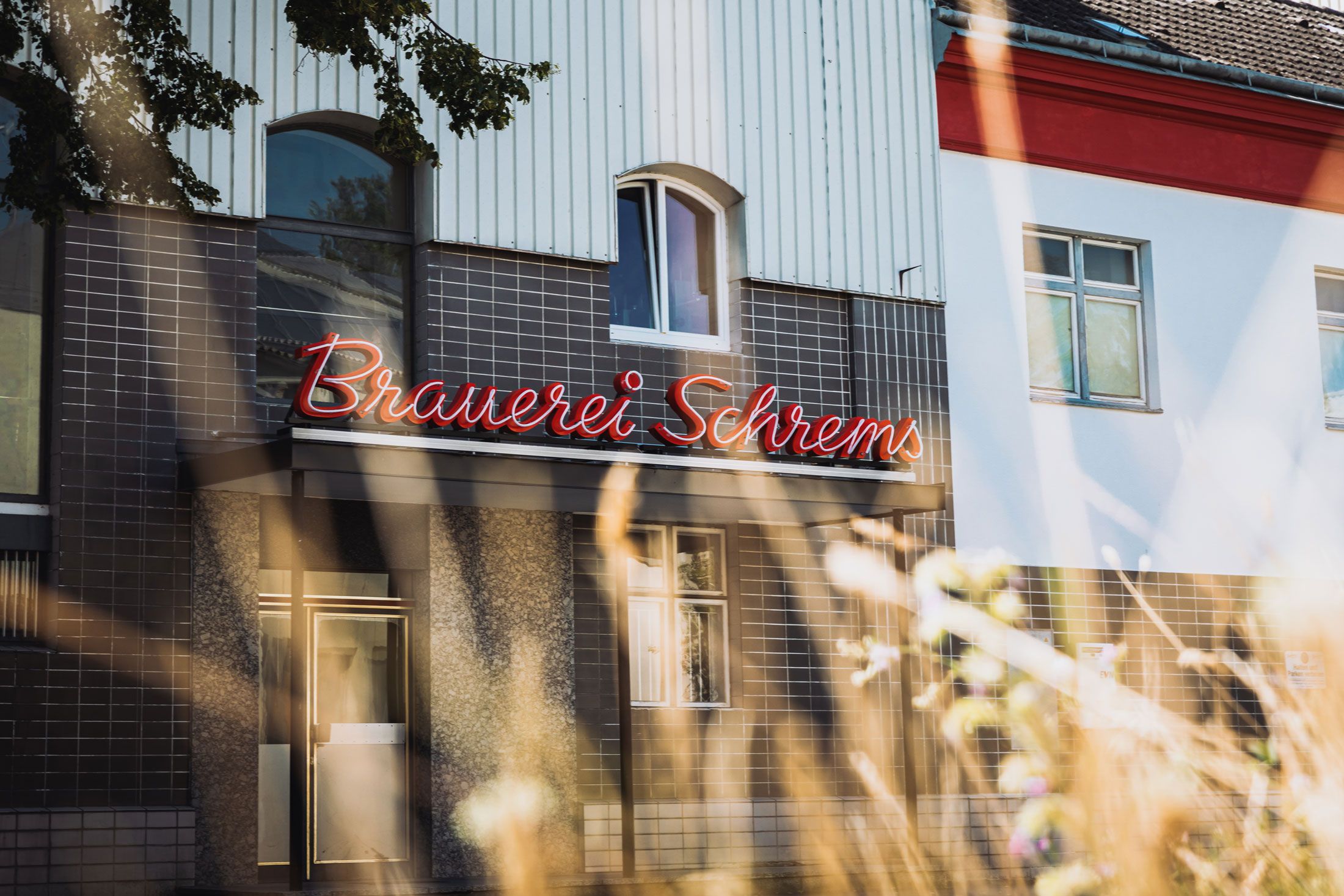 A Schrems sörgyár homlokzata piros világítótáblával.