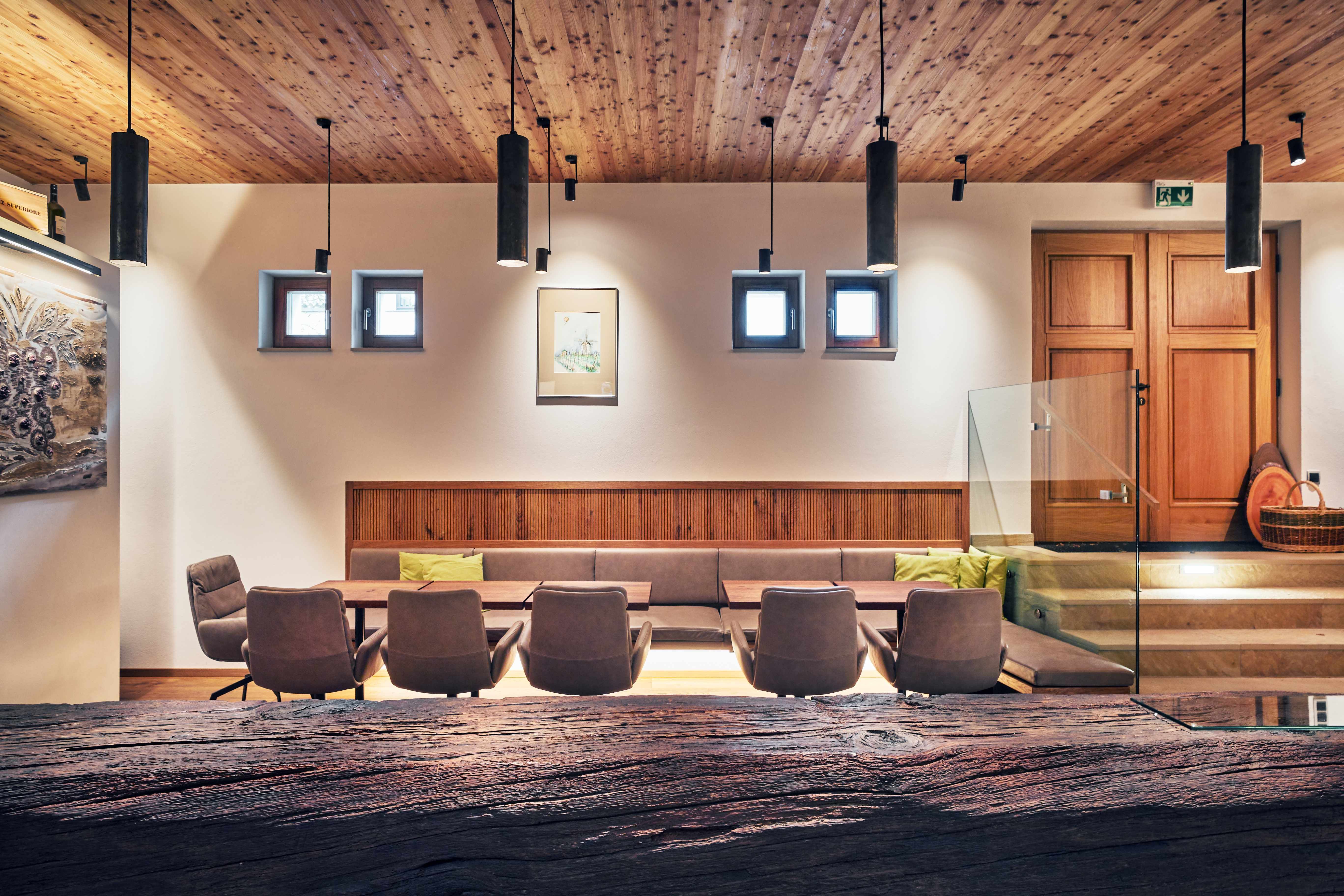 Modern belső tér fa elemekkel, ülőfelülettel és dekoratív lámpákkal.