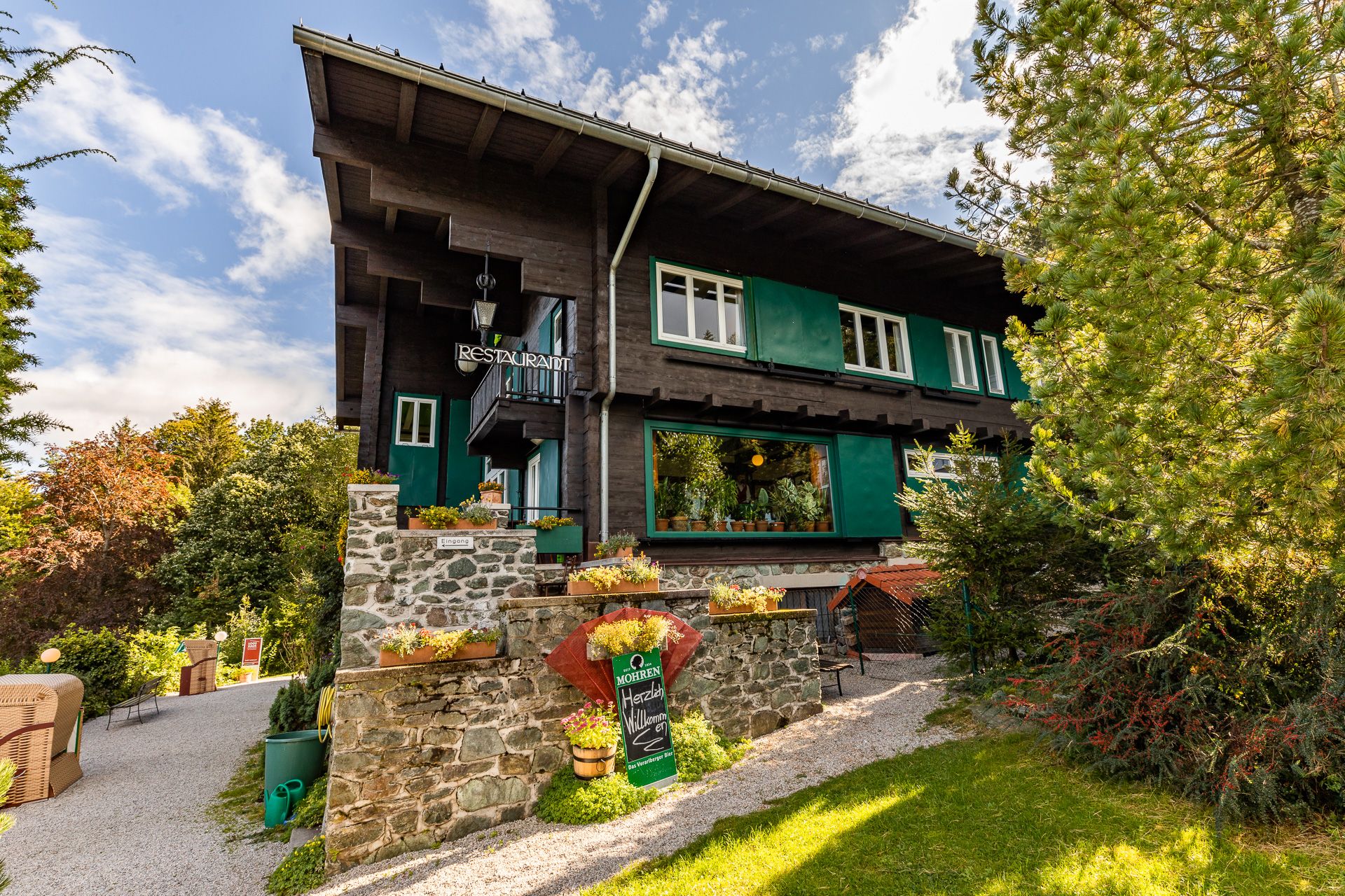 Looshaus am Kreuzberg, egy hagyományos épület étteremmel, fákkal és kerttel körülvéve.