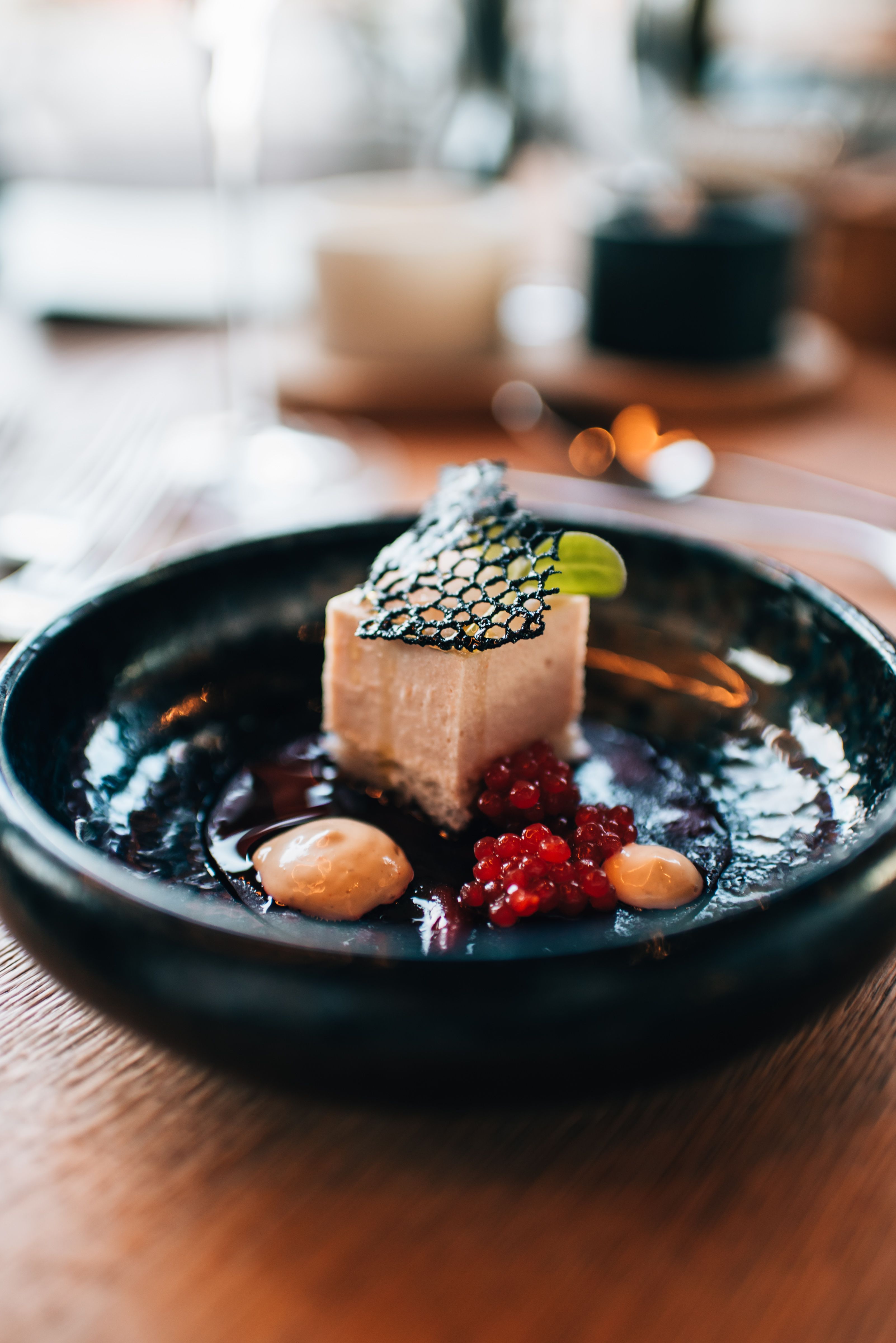 Modern borászat építészete alkonyatkor, megvilágított belső terekkel és a környező épületekkel.