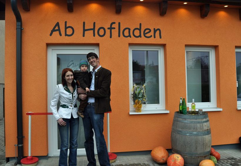 Család a Maria Ellend-i Schäfer-farm boltja előtt, amelyet sütőtökkel és boroshordóval díszítettek fel.