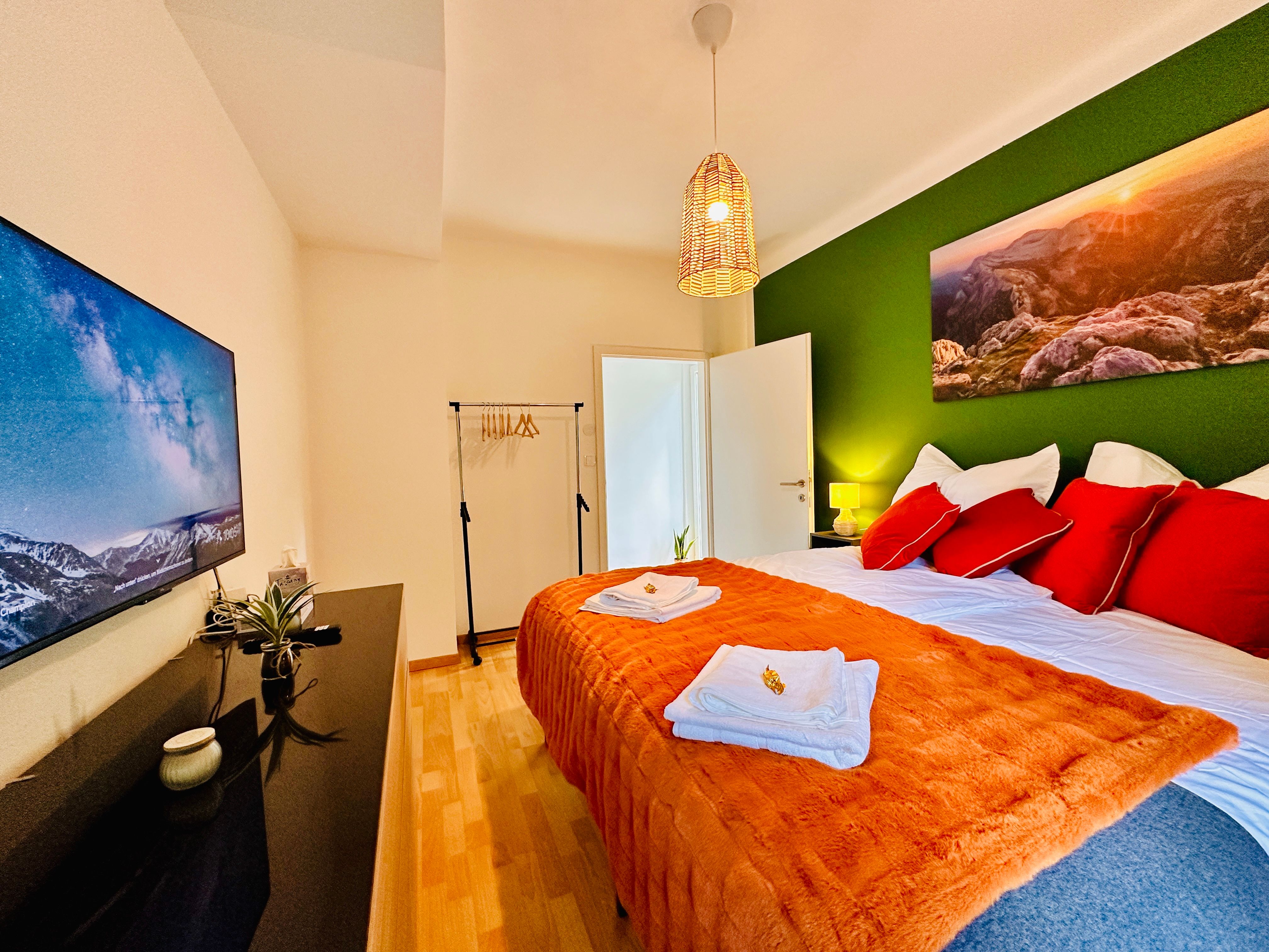 Hangulatos hálószoba zöld akcentussal, franciaággyal, TV-vel és dekorációval.