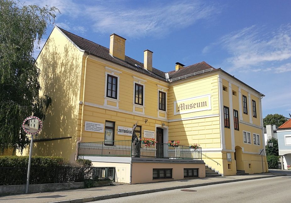 Sárga színű, "Múzeum" és "Zeitbrücke" feliratú épület.