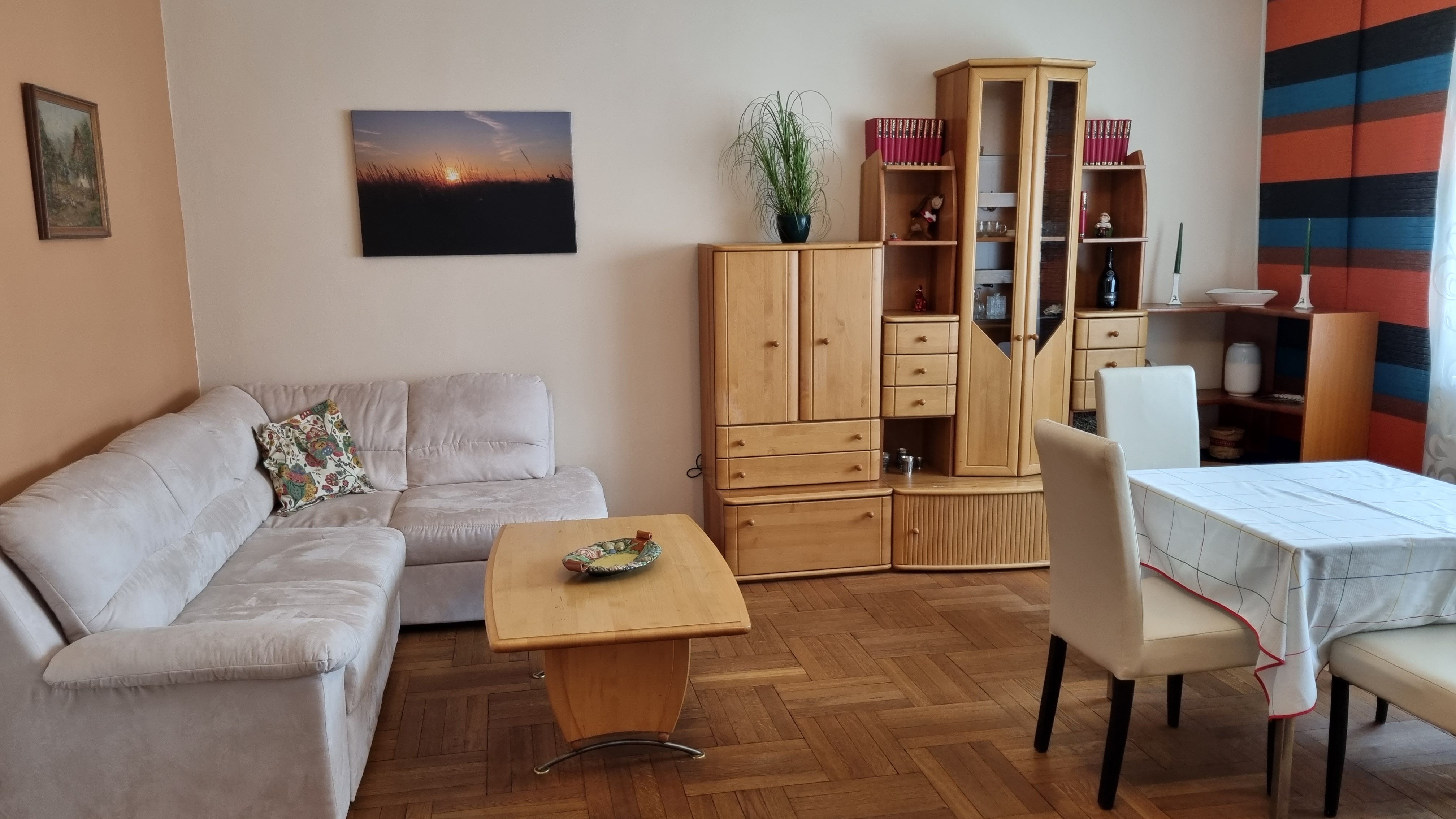 Nappali bézs színű kanapéval, fabútorokkal és étkezőasztallal.