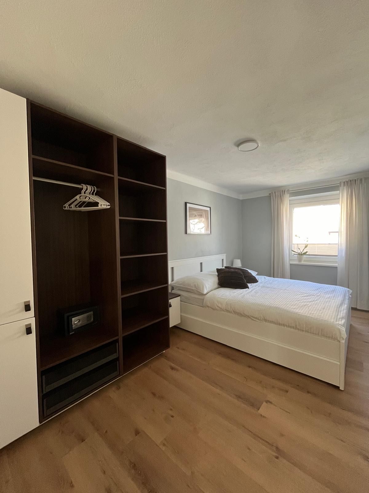 Modern hálószoba franciaággyal, szekrénnyel és függönyös ablakkal.