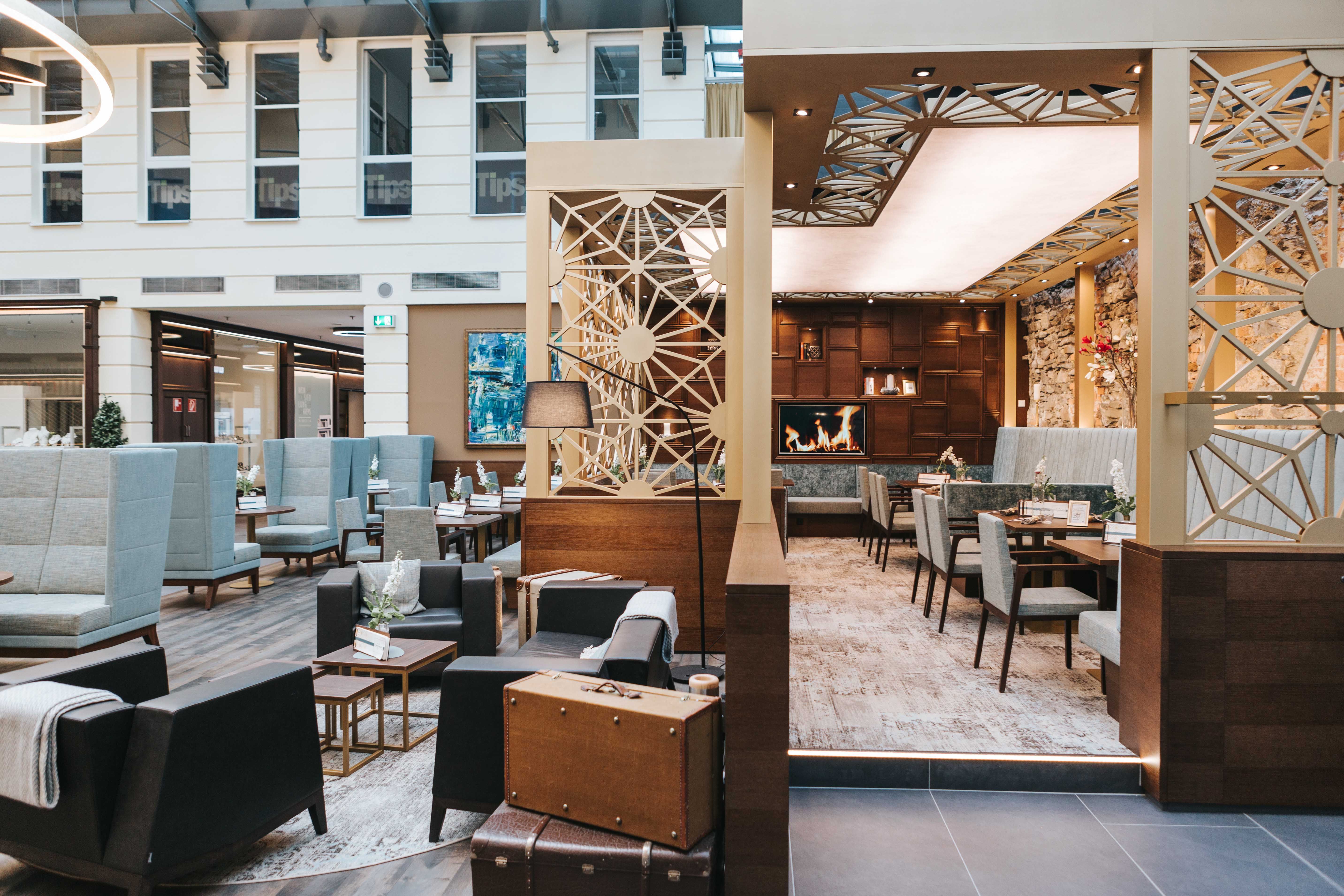 Egy modern kávézó belső nézete, hangulatos ülőhelyekkel, kandallóval és stílusos dekorációval.