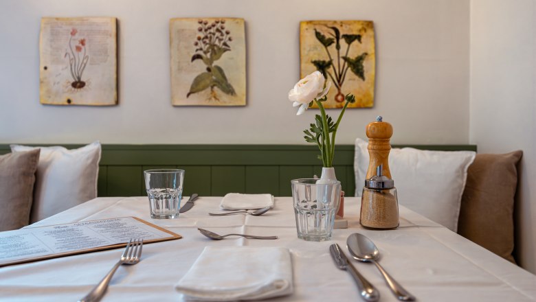 Egy &eacute;tteremben vir&aacute;gokkal &eacute;s fűszerekkel megter&iacute;tett asztal.