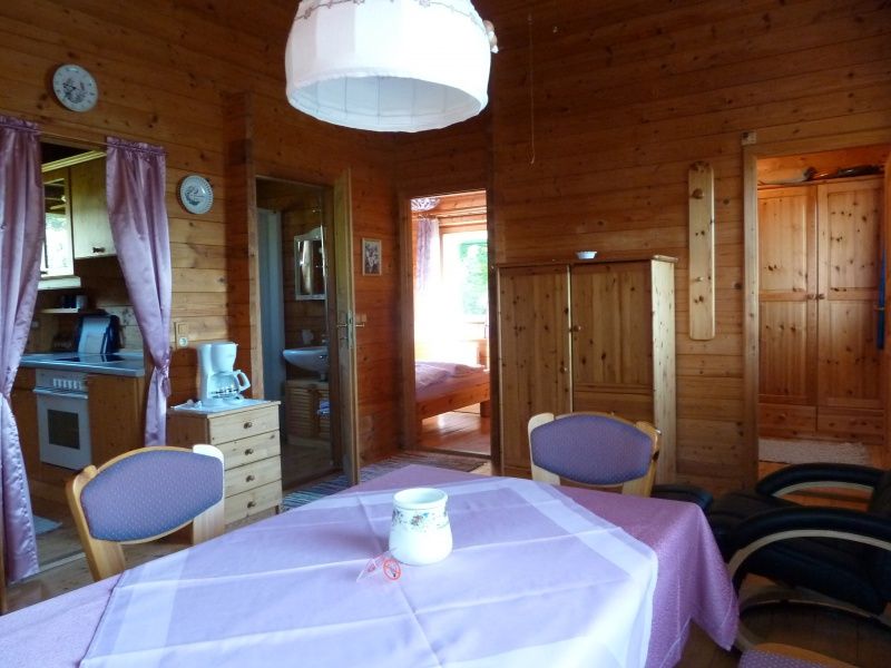 Egy hangulatos nyaraló belső nézete, fából készült falakkal, étkezőasztallal és konyhával.