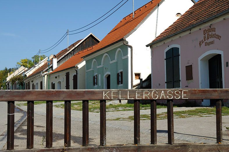 Történelmi pincesor Grafenwörthben, színes épületekkel és fakerítéssel az előtérben.