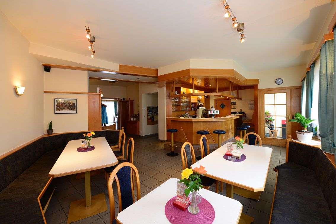 Egy hangulatos étterem belső nézete, asztalokkal, székekkel és bárral.