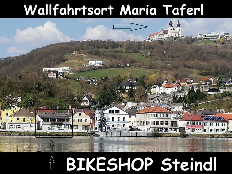 Maria Taferl látképe egy dombon álló templommal, a falu alatt és a Steindl kerékpárbolt feliratával.