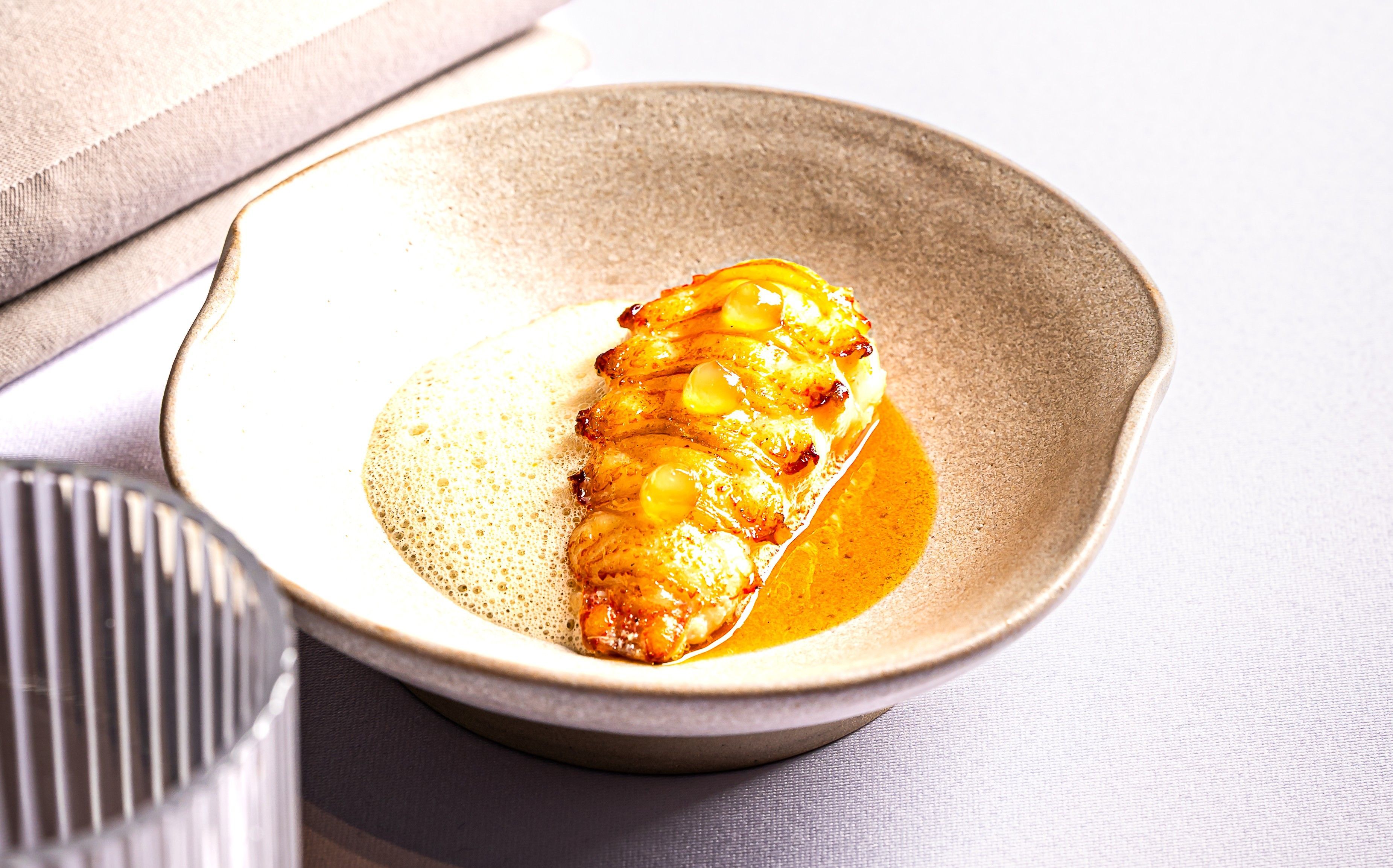 Művészien elkészített étel egy tálban, habbal és mártással.