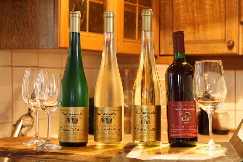 Négy borosüveg és pohár egy konyhai asztalon.