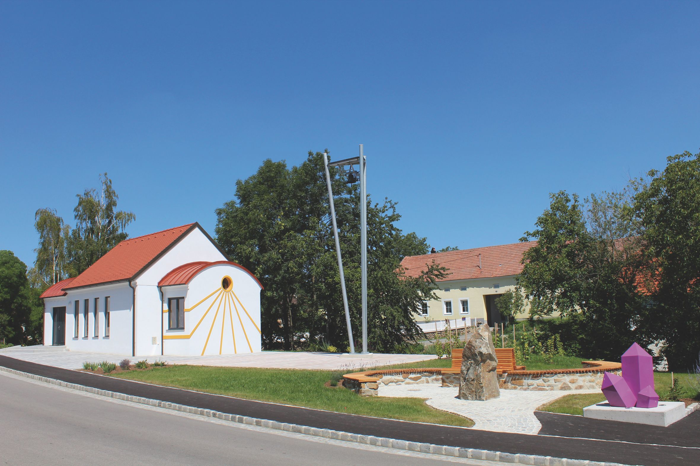 Fehér kápolna vörös tetővel és ametiszt szoborral az előtérben.