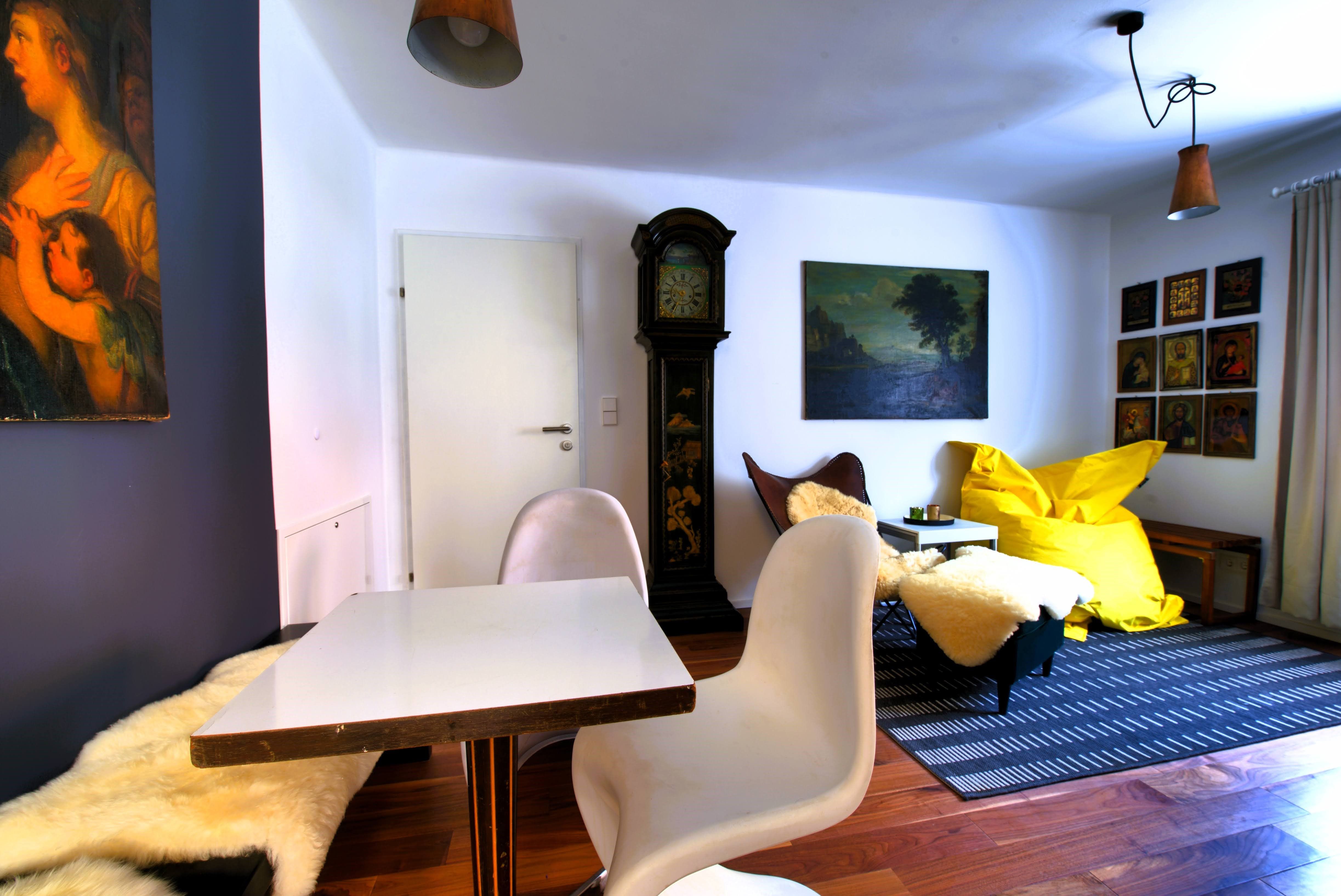 Nappali asztal, székek, nagypapa óra, festmények és sárga babzsák.