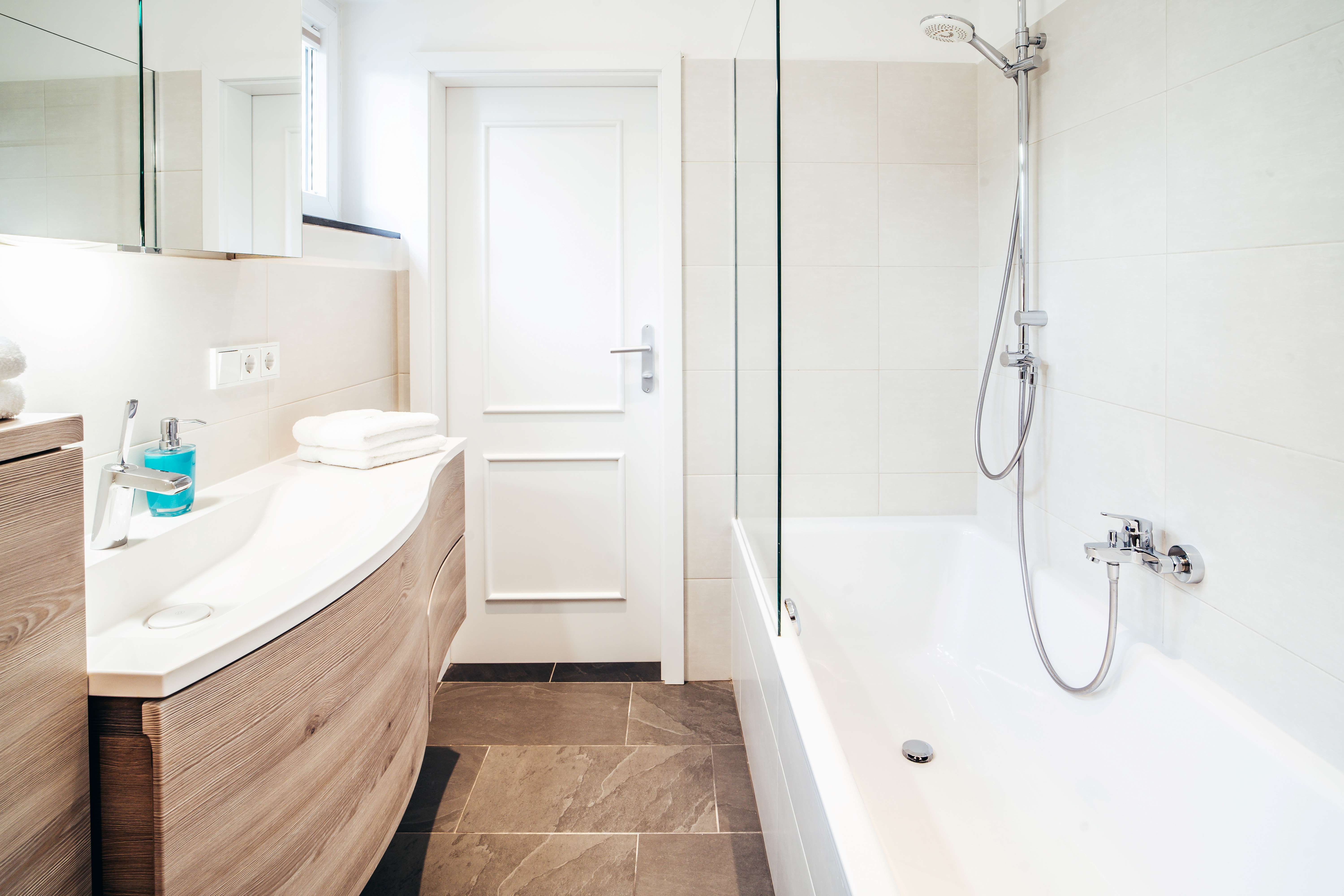 Modern fürdőszoba káddal, mosdóval és tükörrel.