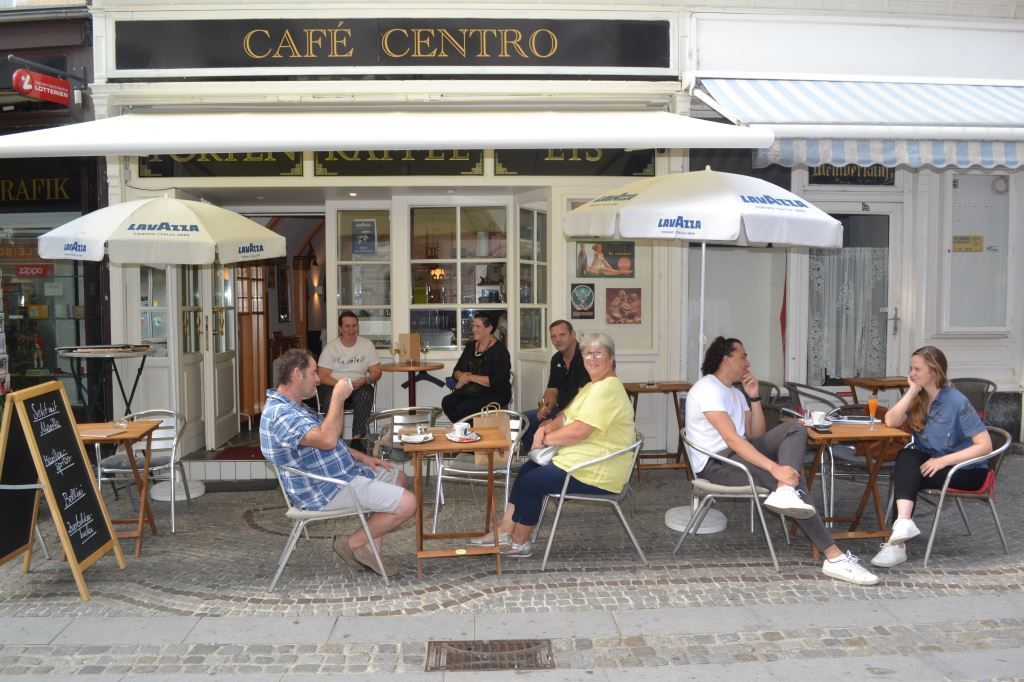 Az emberek a Café Centro nevű kávézó előtt ülnek.