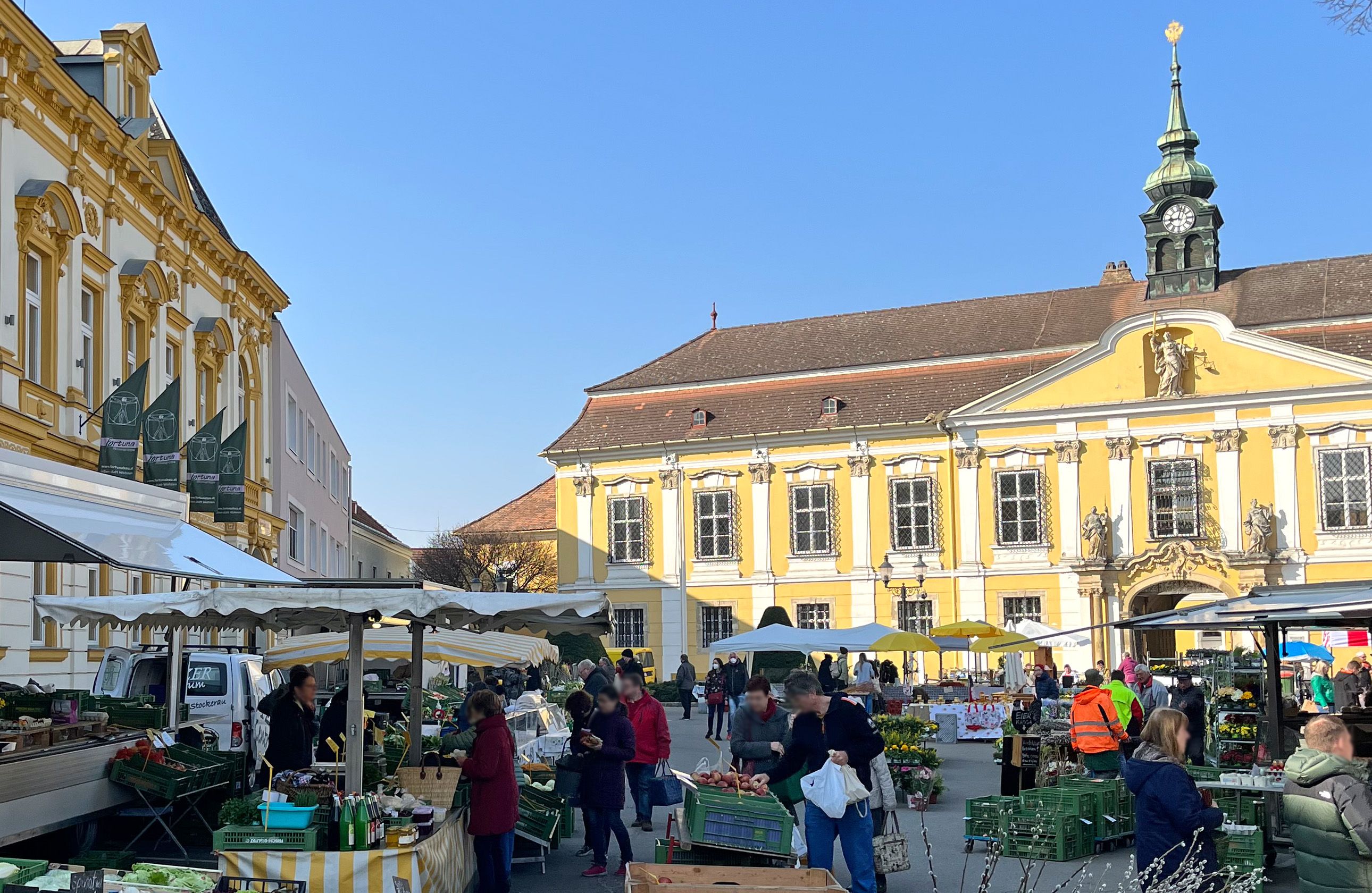 Heti piac Stockerau-ban, háttérben történelmi épületekkel.