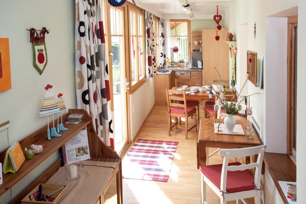 Hangulatos apartman fából készült bútorokkal, étkezőasztallal és dekoratív függönyökkel.