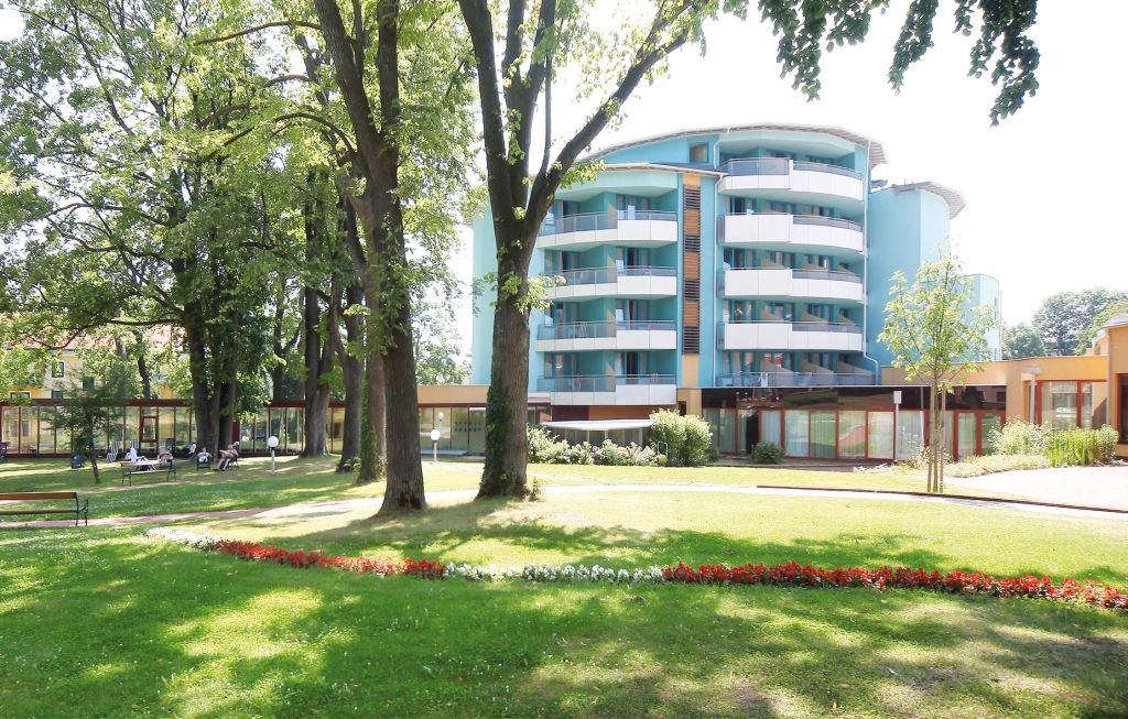Modern épület erkélyekkel és kerttel az előtérben.