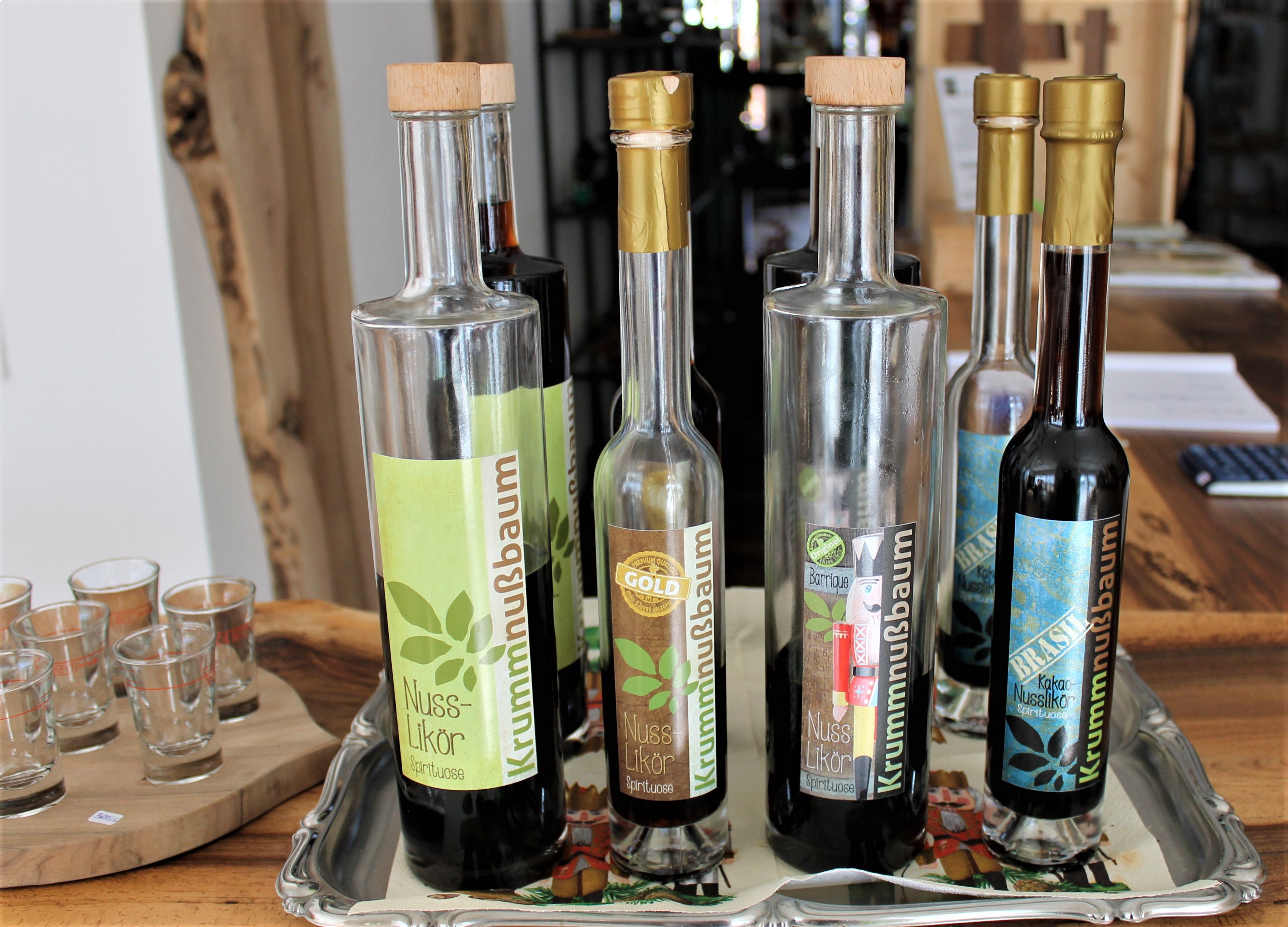 Több üveg diólikőr egy tálcán, mellette poharakkal.