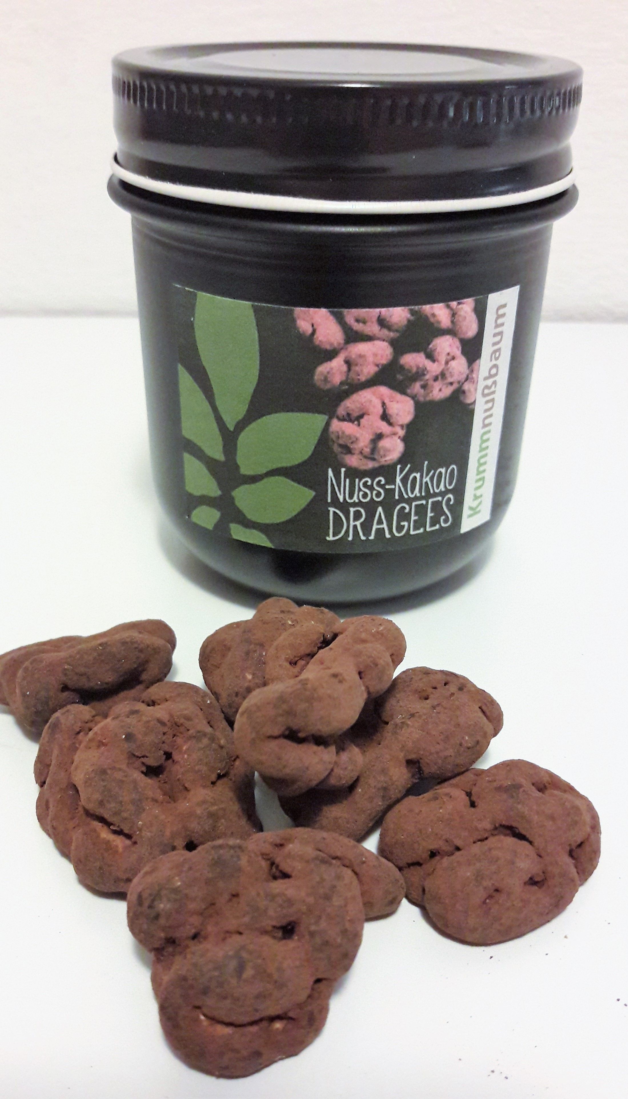 Egy "Nuss-Kakao Dragees" feliratú edény és előtte néhány drazsé.