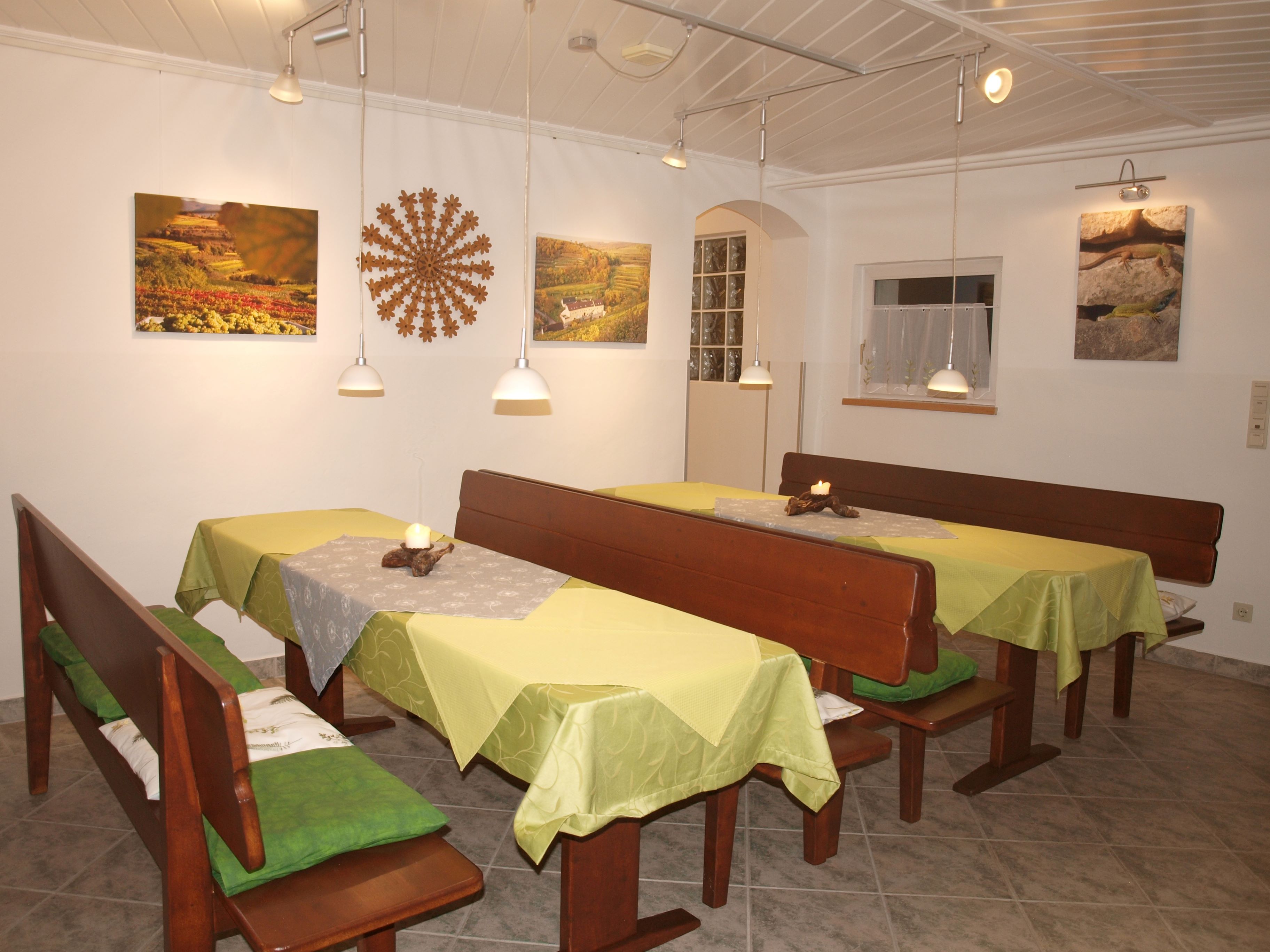 Hangulatos reggelizőhelyiség fapadokkal, zöld terítőkkel és fali dekorációval.