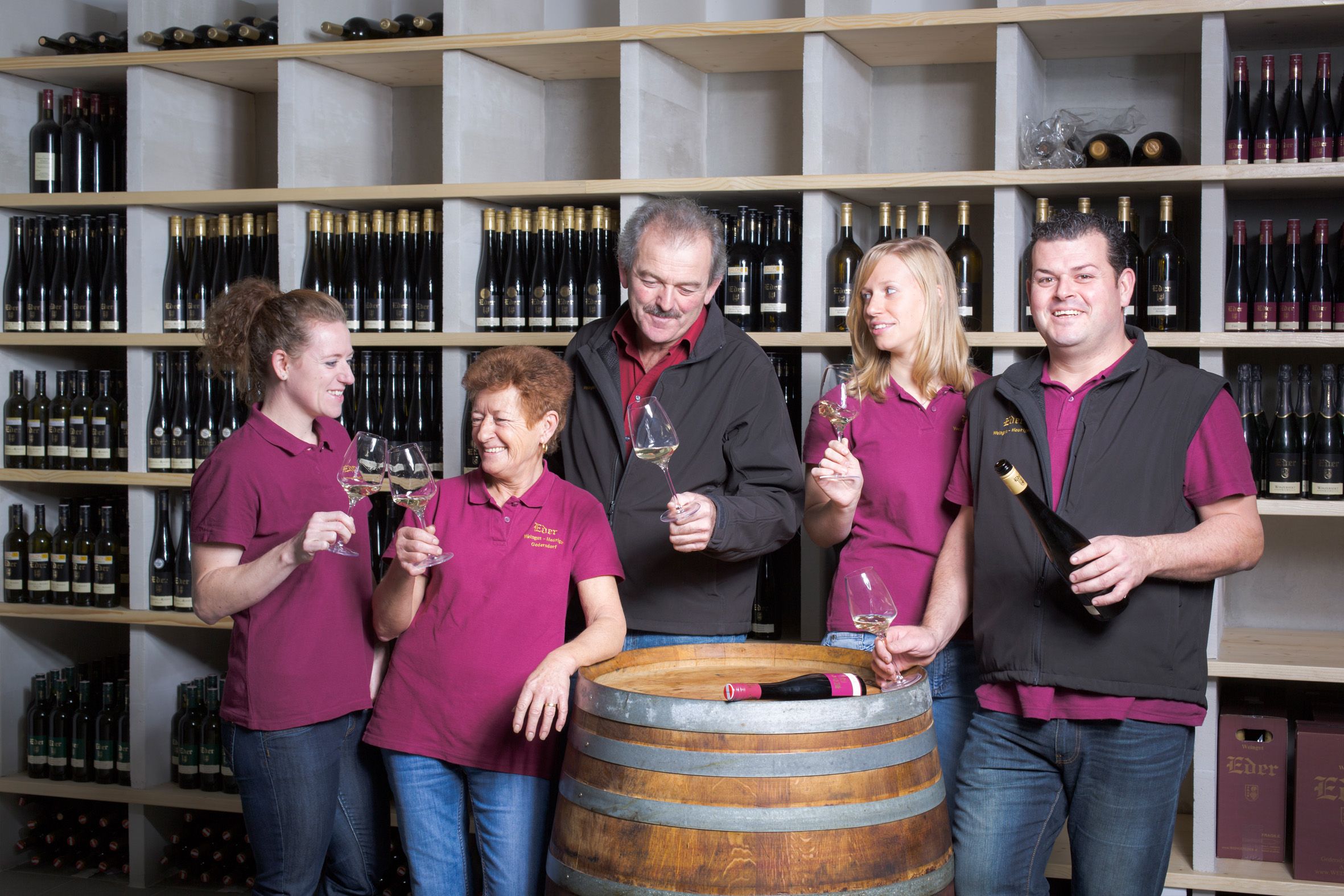 Öt ember egy borospincében koccint a poharakkal.