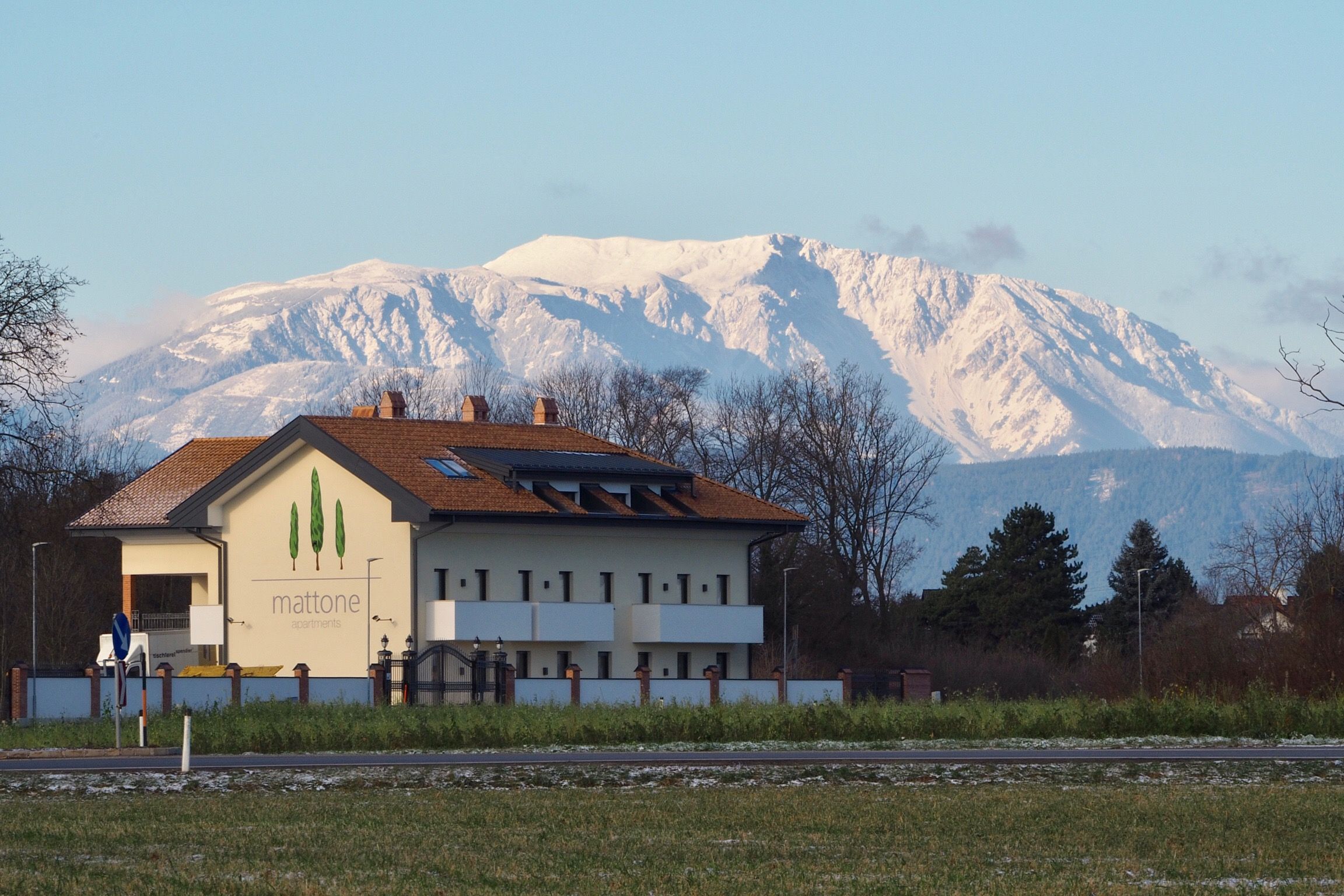 "Mattone flats" feliratú épület a háttérben hófödte hegy előtt.