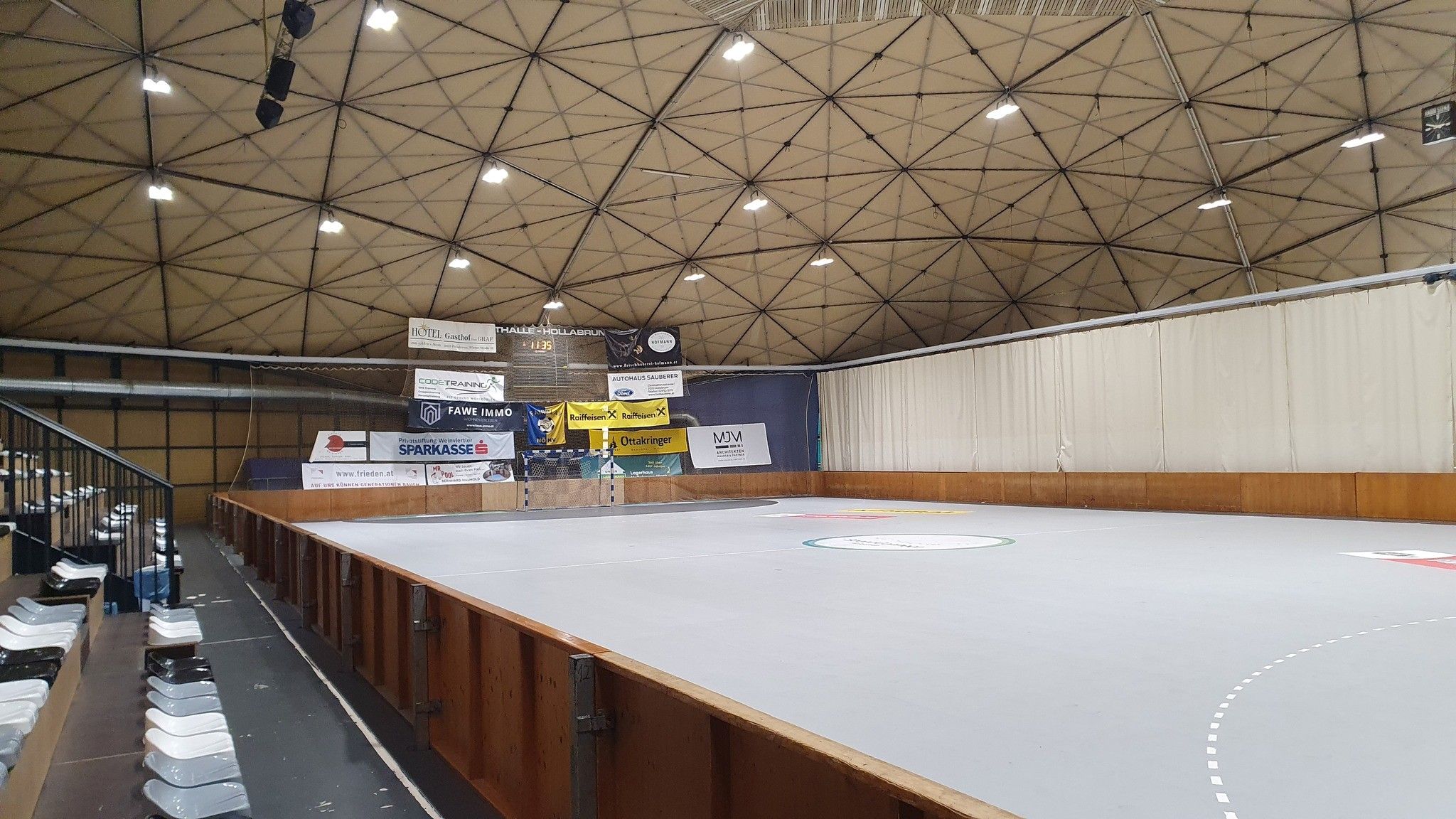 A hollabrunni sportcsarnok belső nézete üres lelátóval és játéktérrel.