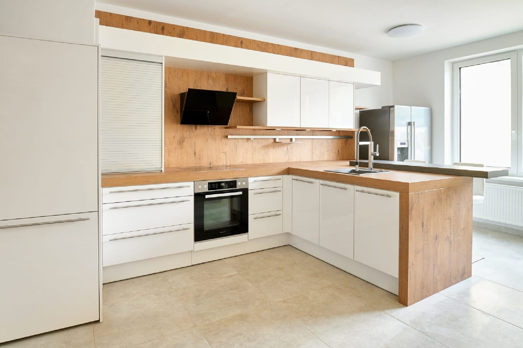 Modern konyha fa és fehér tónusokkal, tűzhely, mosogató és nagy ablak.