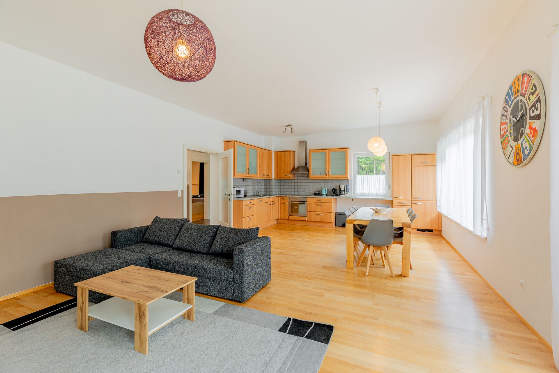 Nyitott terű nappali konyhával, étkezőasztallal és kanapéval.