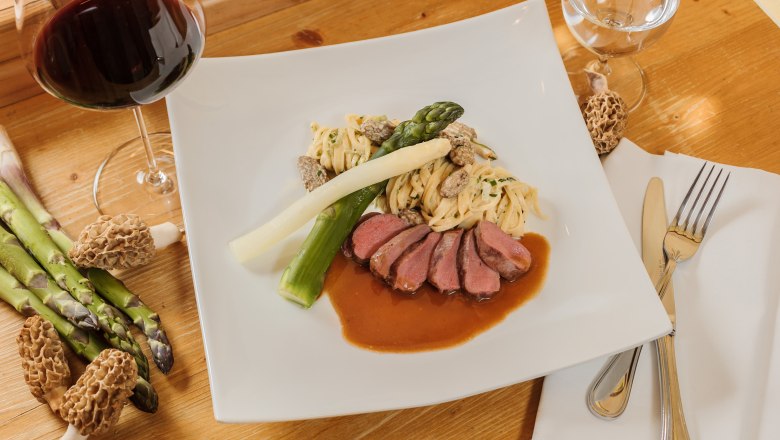 Gourmet &eacute;tel h&uacute;ssal, sp&aacute;rg&aacute;val, t&eacute;szt&aacute;val &eacute;s morzs&aacute;val feh&eacute;r t&aacute;ny&eacute;ron, mell&eacute; egy poh&aacute;r v&ouml;r&ouml;sbor.