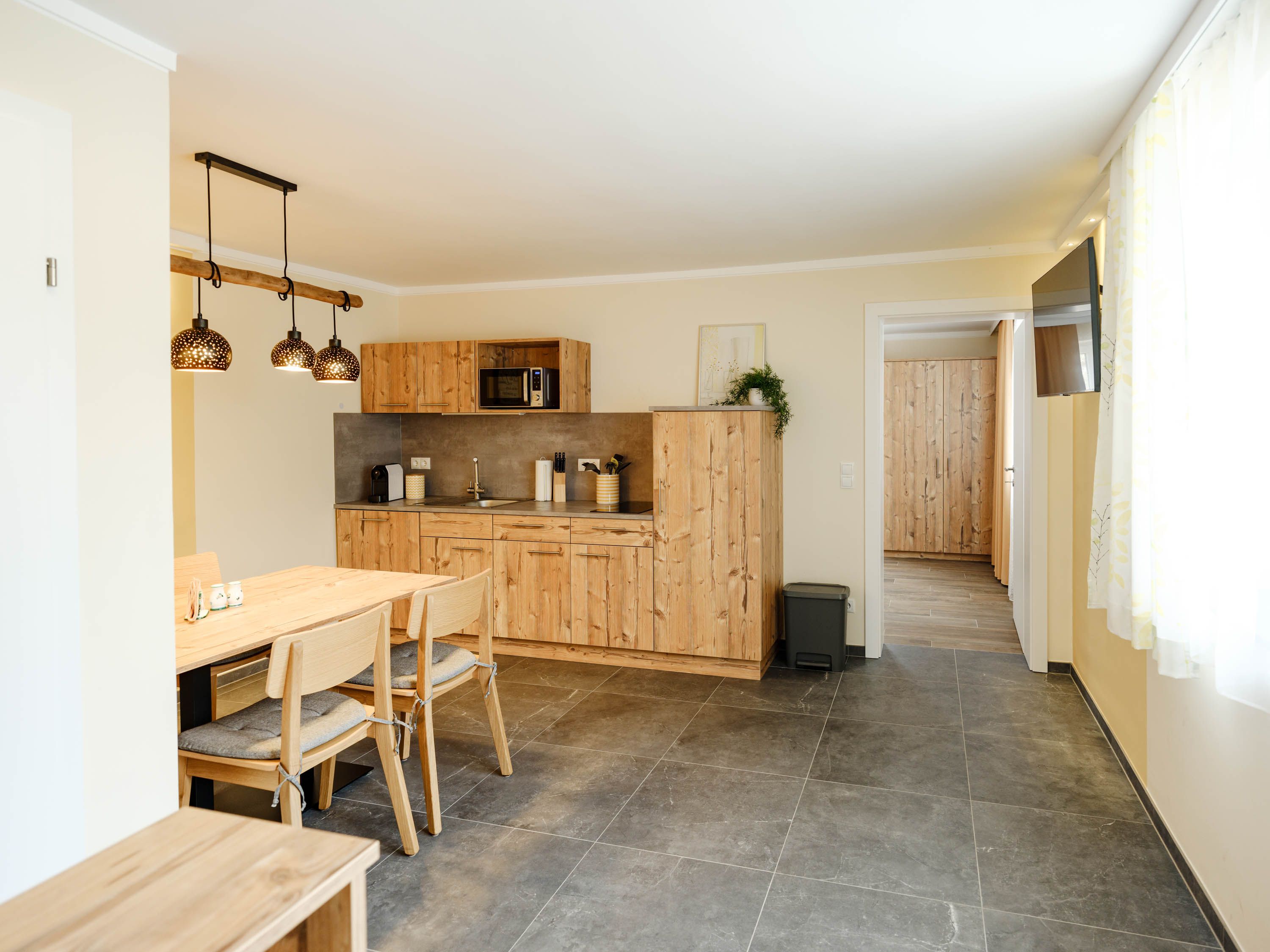 Modern konyha fa bútorokkal és étkezőasztallal, világos világítással.