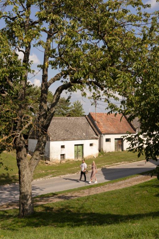 Két ember sétál régi épületek mellett egy vidéki környezetben.