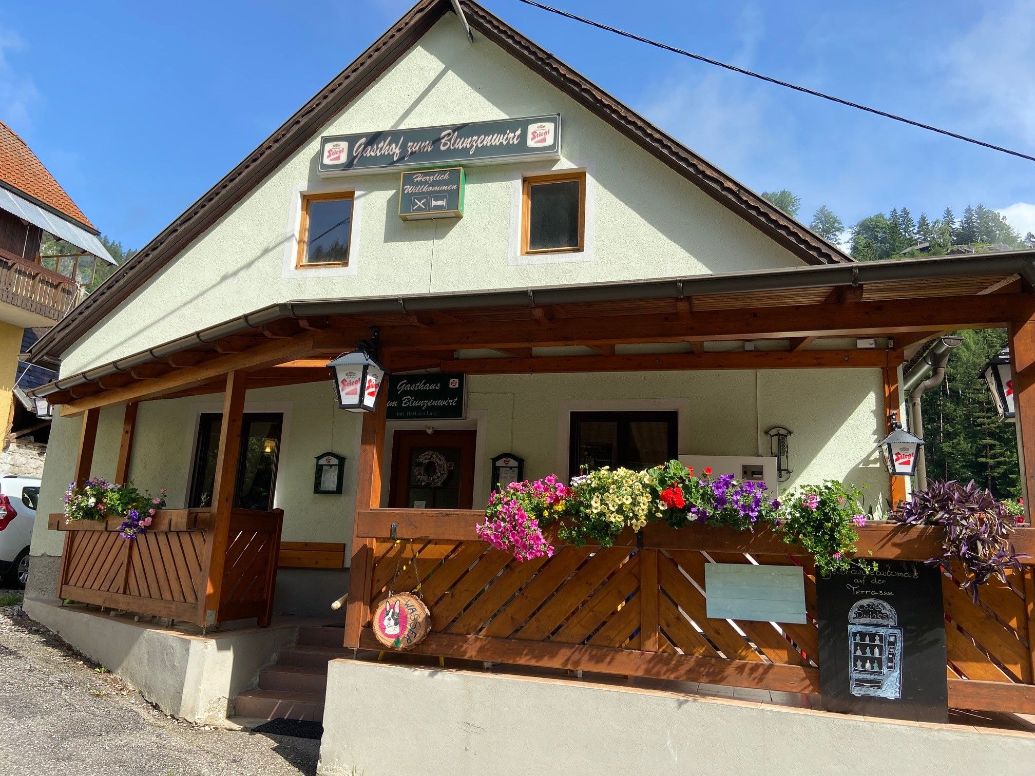 A "Gasthof zum Blunzenwirt" feliratú, fából készült verandával és virágládákkal rendelkező hagyományos vendéglő.