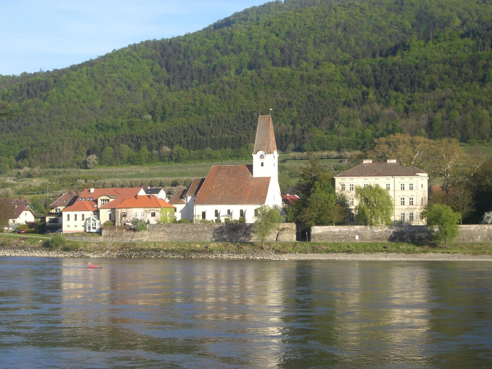 Hofarnsdorf vára és temploma a Dunán, háttérben egy erdős domb.