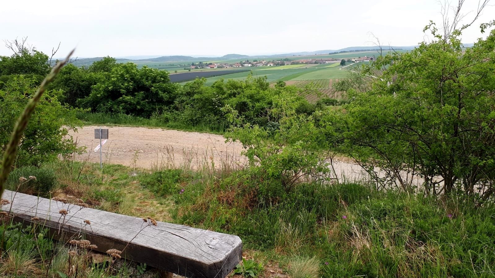 Tájkép paddal, fákkal és mezőkkel a távolban.