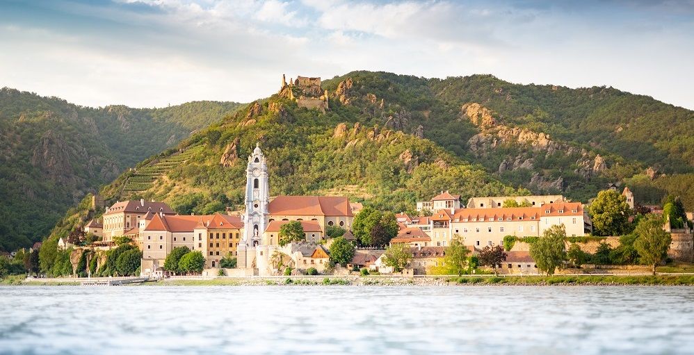 Dürnstein látképe kolostorral és várromokkal az erdős dombok előtt.