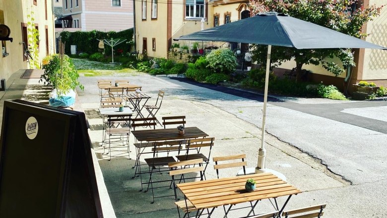 A belső udvaron f&aacute;b&oacute;l k&eacute;sz&uuml;lt asztalokkal &eacute;s sz&eacute;kekkel, napernyővel &eacute;s n&ouml;v&eacute;nyekkel berendezett vend&eacute;gkert.