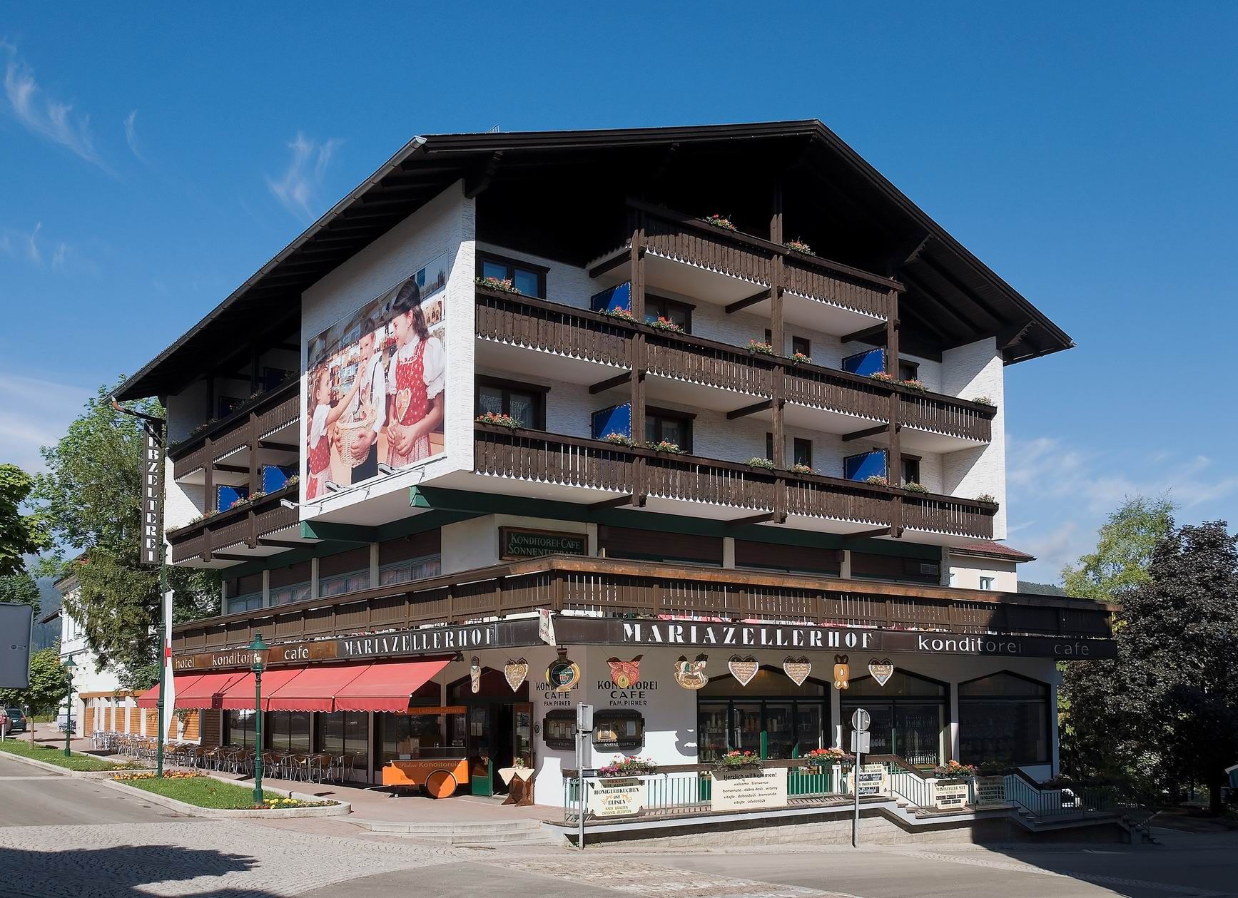 A Hotel Pirker Mariazellerhof külső nézete erkélyekkel és kávézóval.