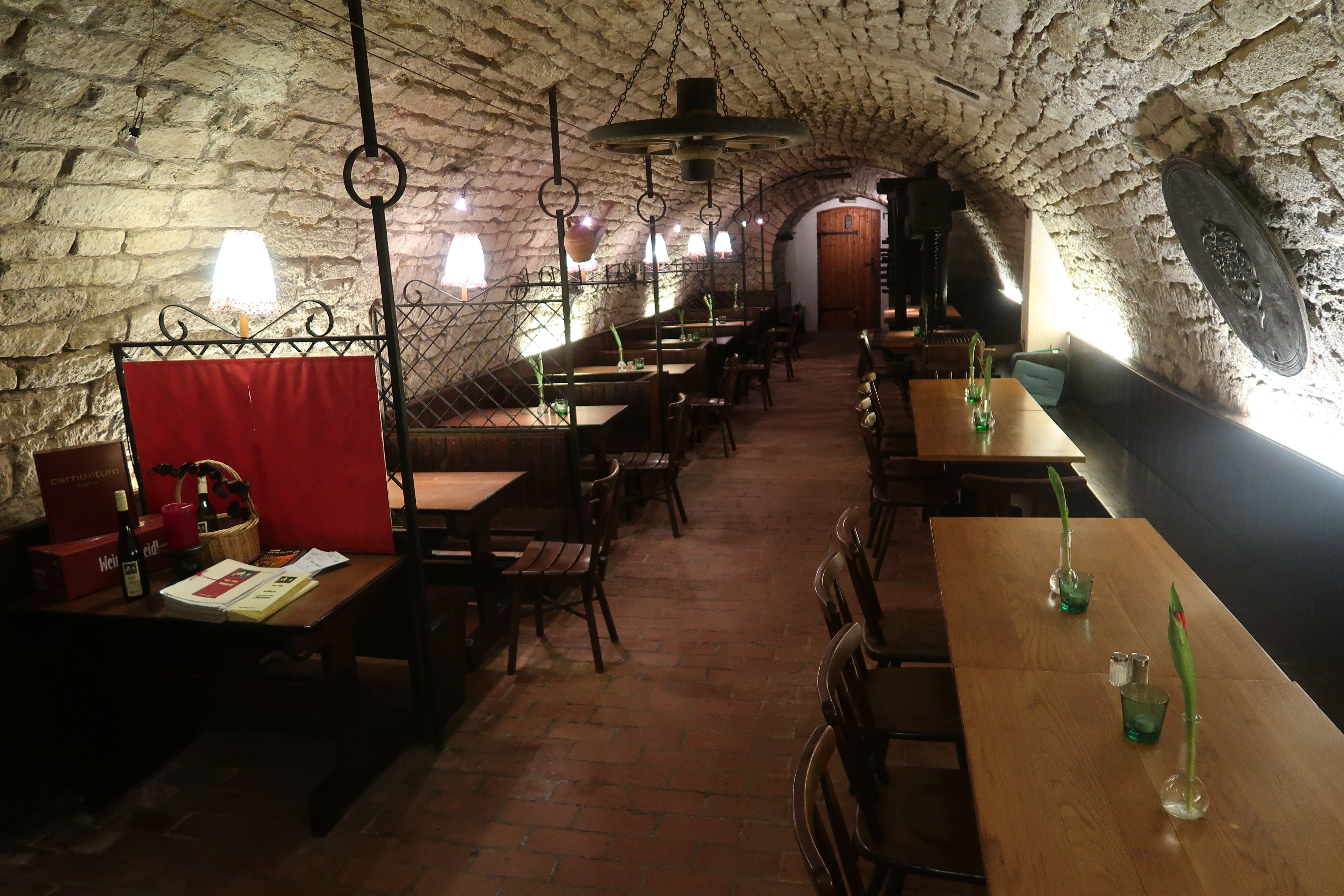 Kőboltozatos pince asztalokkal és fotelekkel 