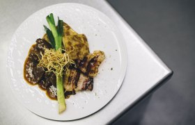 Egy t&aacute;ny&eacute;r s&uuml;lt marhah&uacute;ssal, burgonyagratinnal, p&oacute;r&eacute;hagym&aacute;val &eacute;s ropog&oacute;s hagym&aacute;val f&eacute;m fel&uuml;leten.