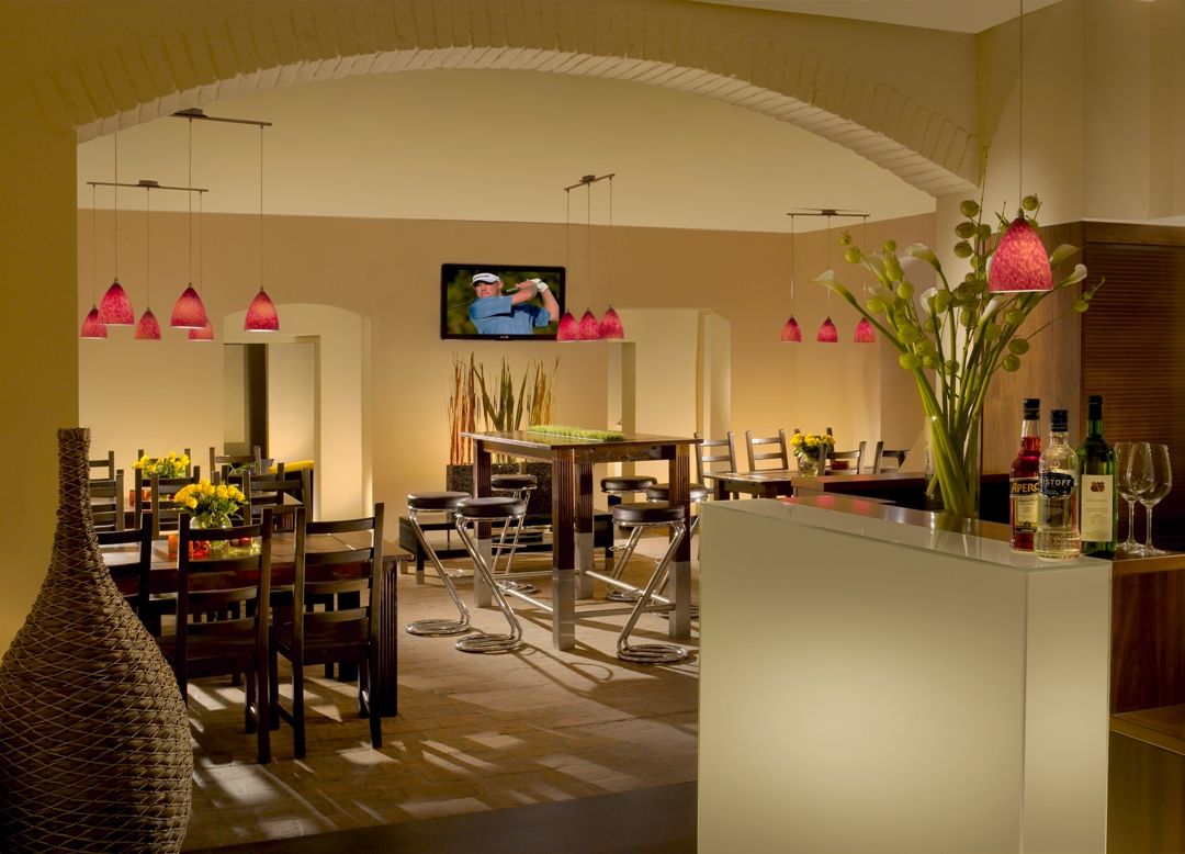 Egy elegáns étterem belső nézete, modern bútorokkal és piros lógó lámpákkal.