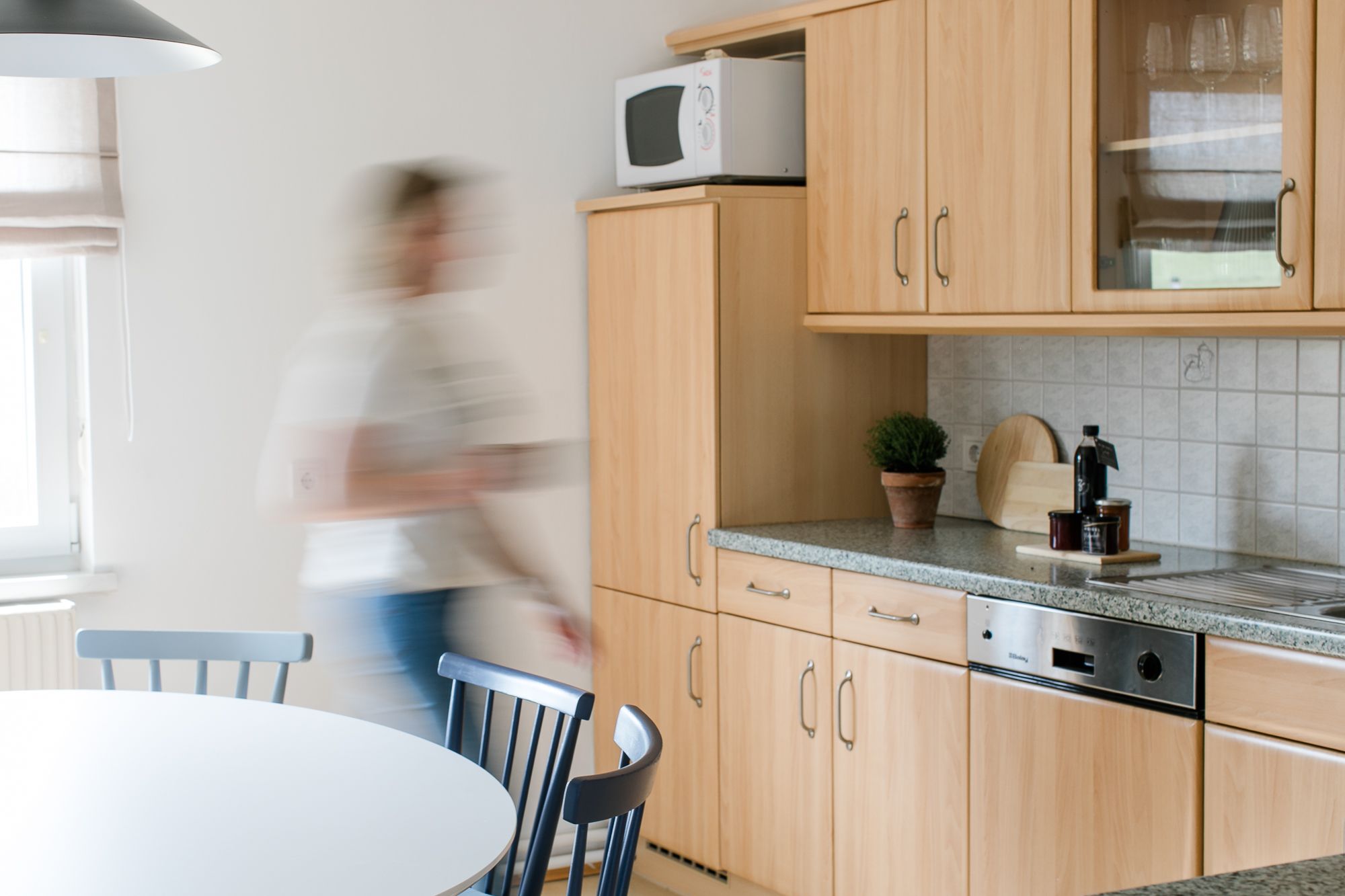 Modern konyha fa bútorokkal és egy mozgó személy.