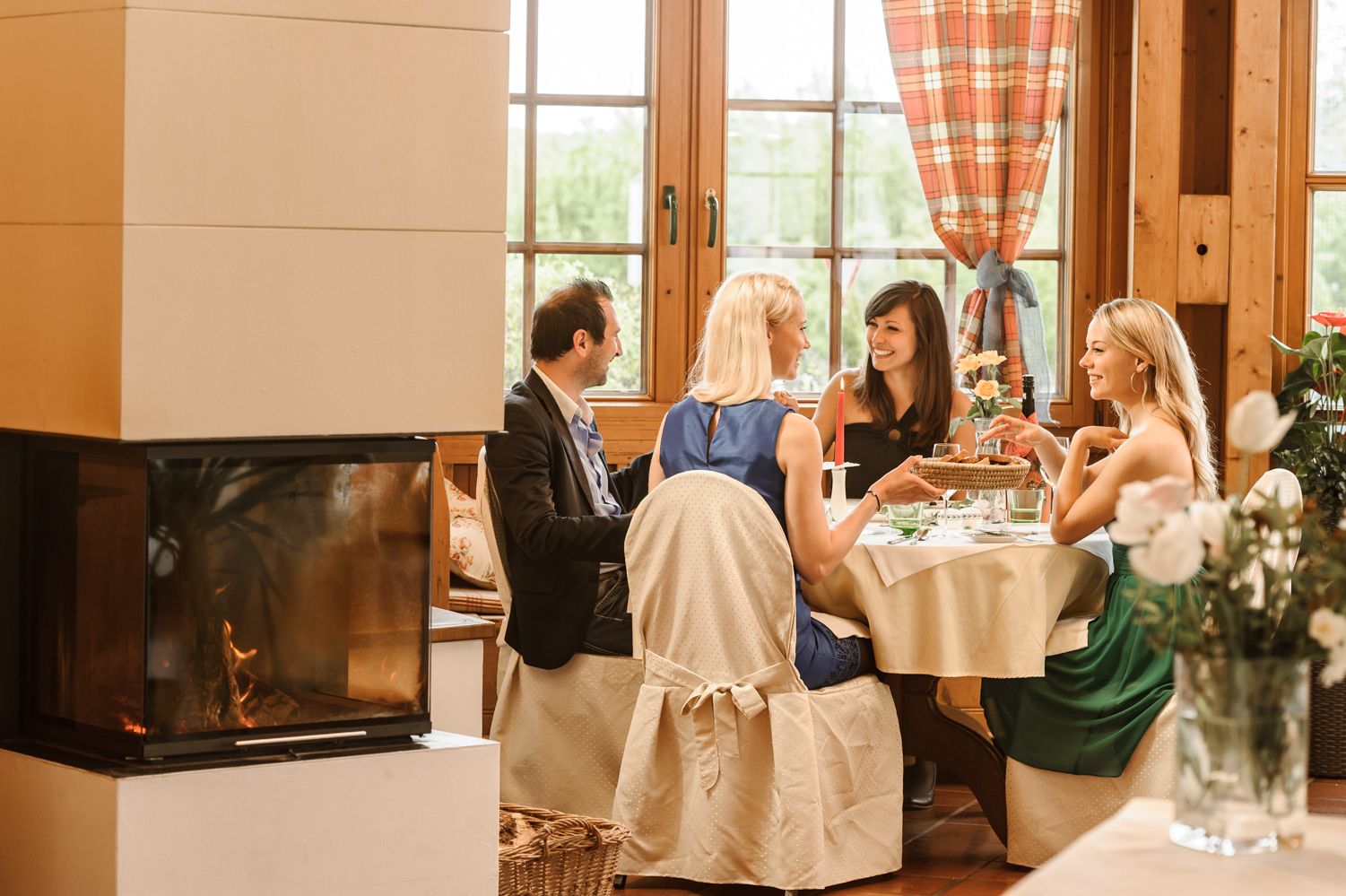 Négyen ülnek egy asztalnál a hangulatos, kandallós télikertben.