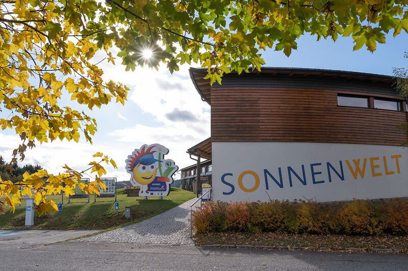 A SONNENWELT Großschönau bejárata őszi fákkal és napsütéssel.