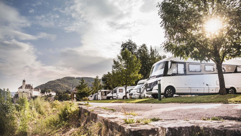 Lak&oacute;aut&oacute;k egy kempingben, a h&aacute;tt&eacute;rben egy kast&eacute;llyal.