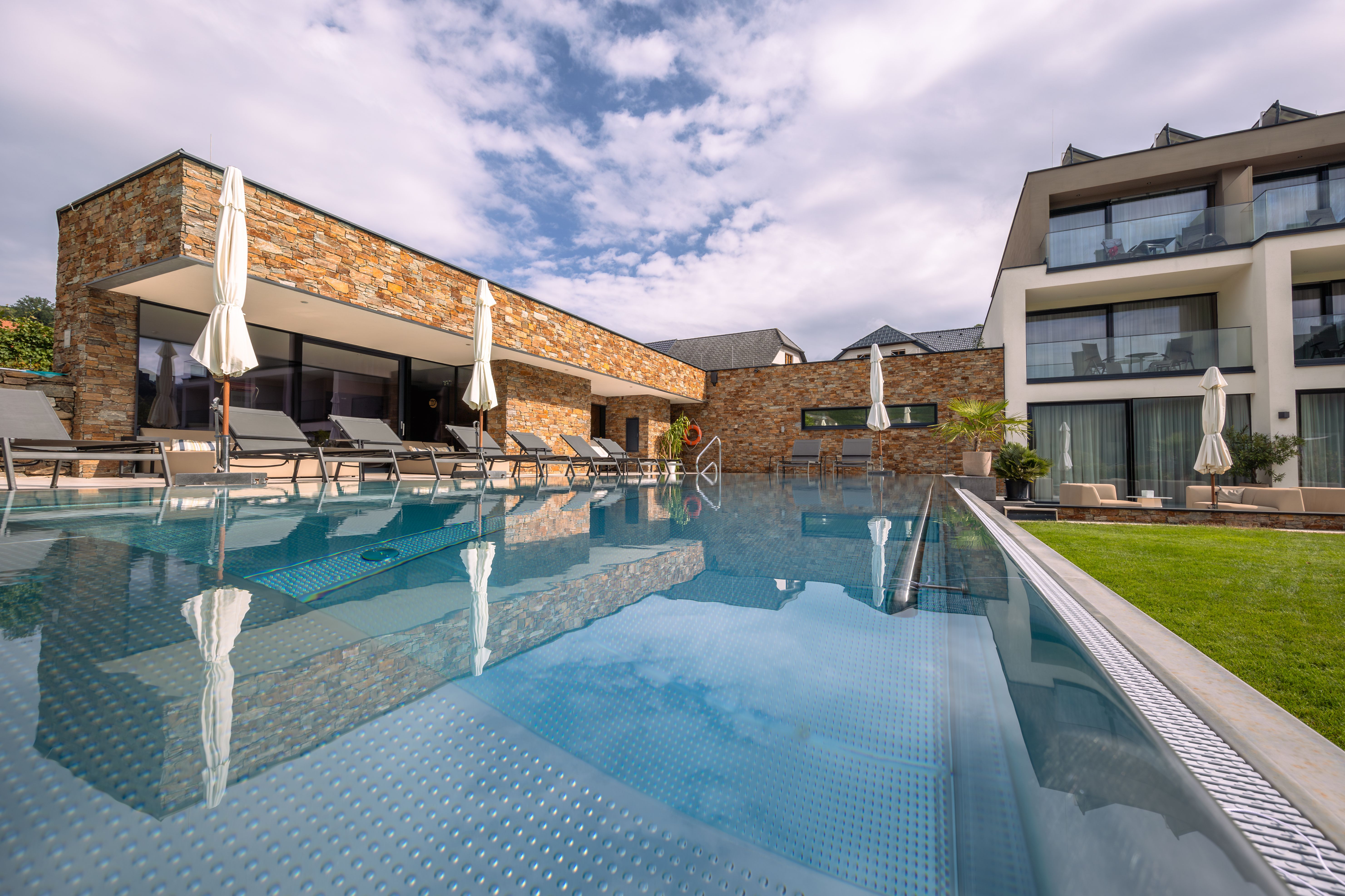 Egy modern szálloda külső nézete medencével és nyugágyakkal.