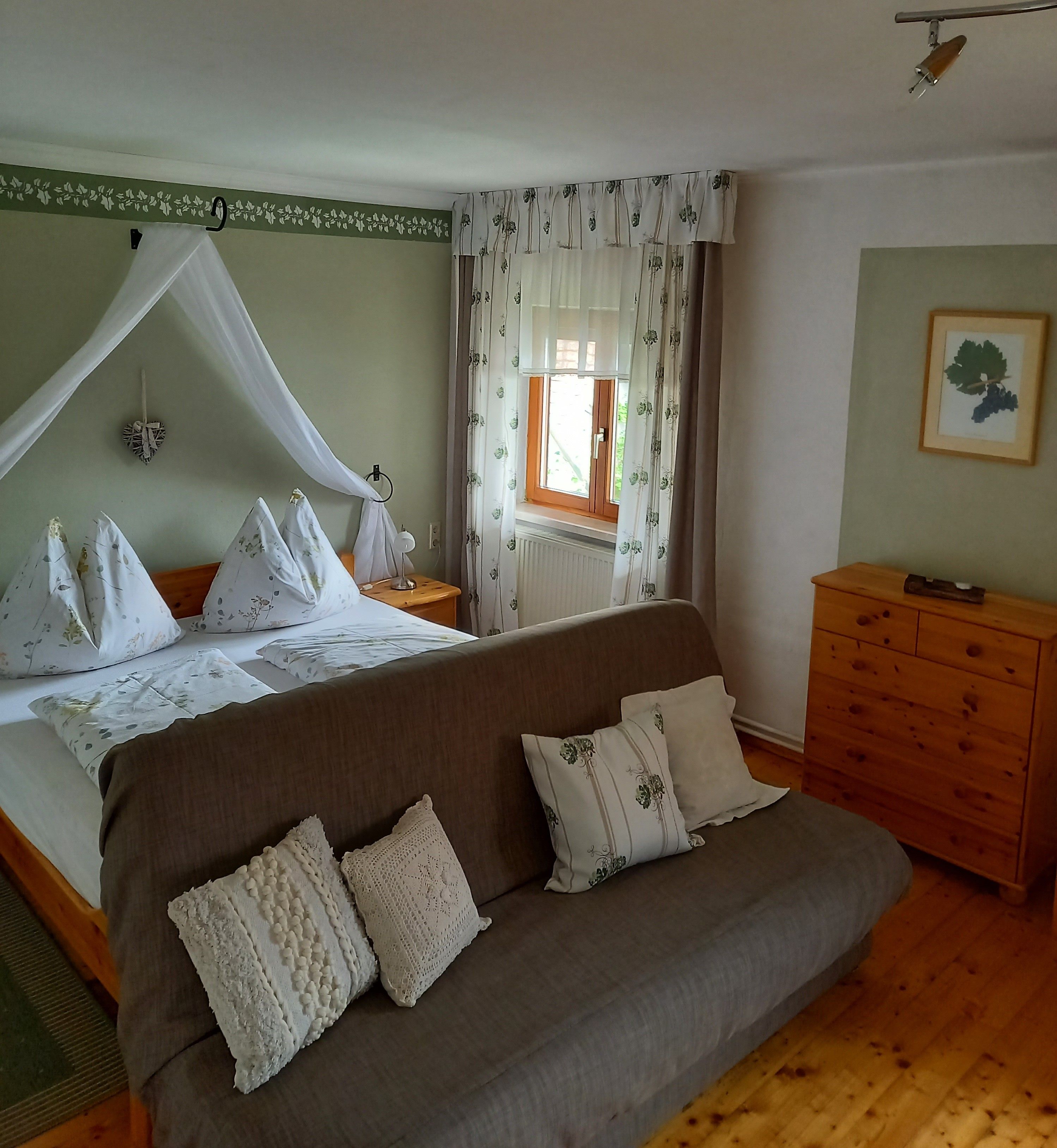 Hangulatos vendégszoba franciaággyal, kanapéval és fabútorokkal.